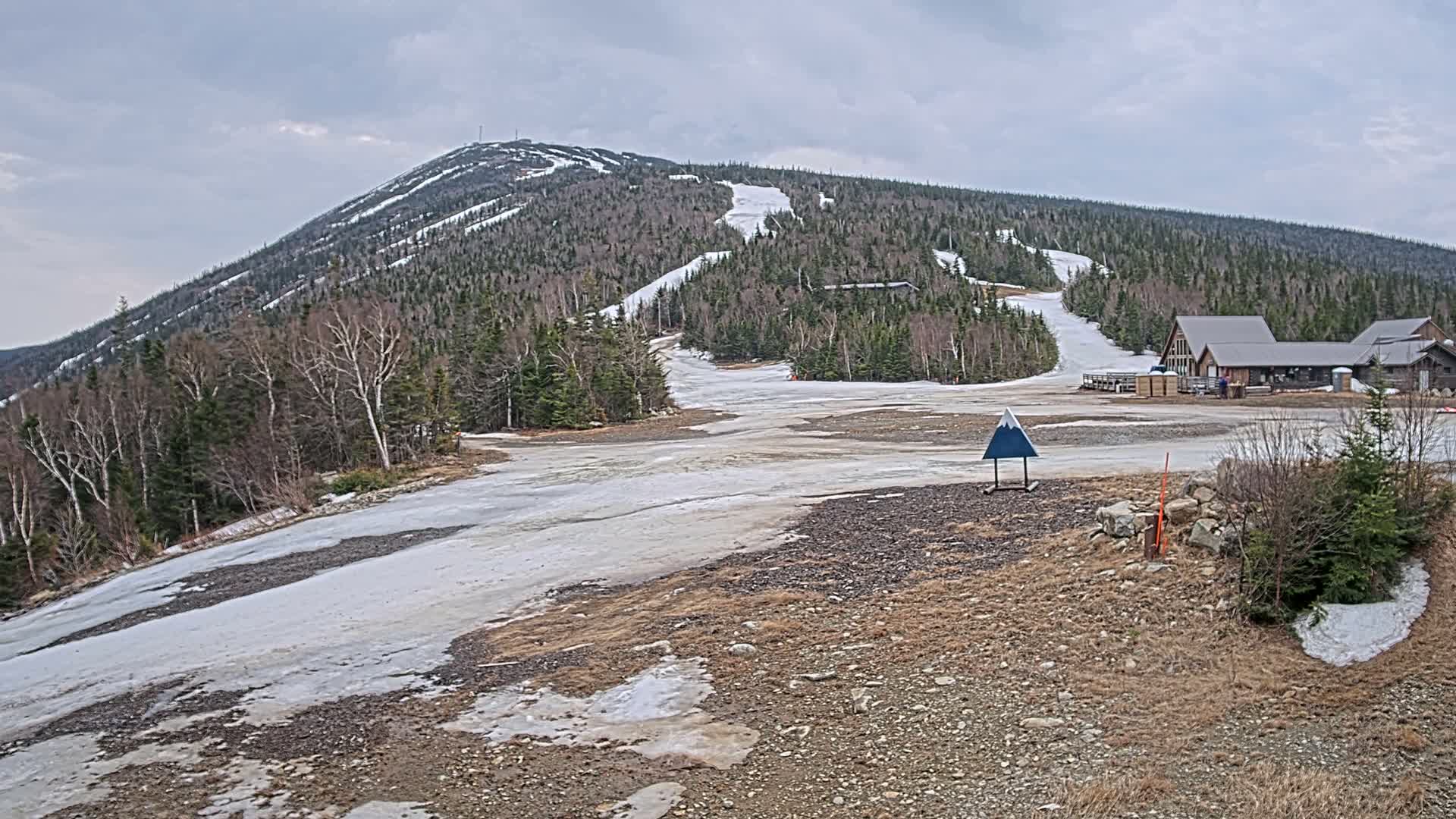 It is a clear, cold night at a snow-covered ski resort where snow guns are actively producing snow, with distant evergreen forests and lodge buildings visible under a starry, moonlit sky.