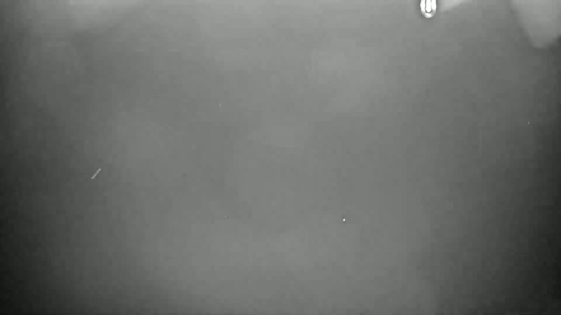A blurry, dark gray image shows a very foggy or hazy scene with a few small, indistinct specks.