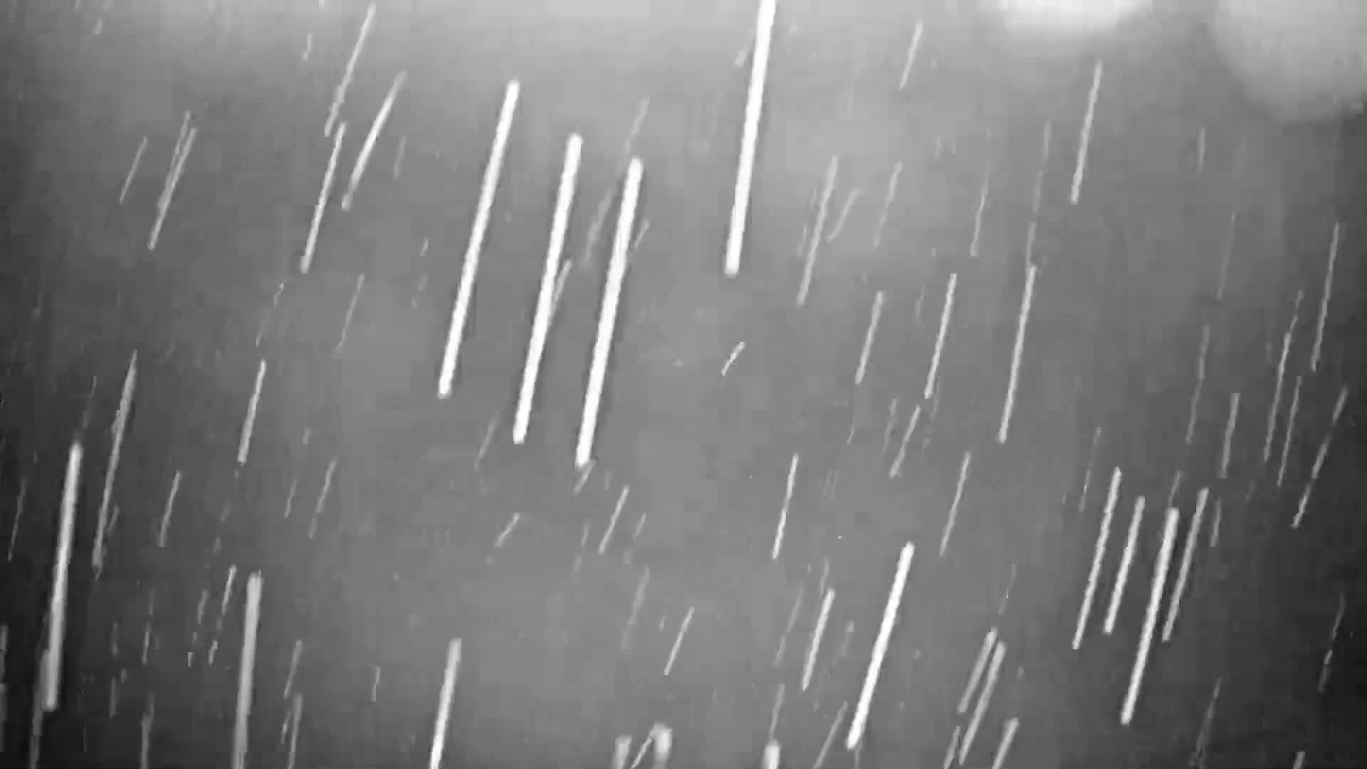Numerous streaks of white appear to fall against a dark gray background in heavy rain.