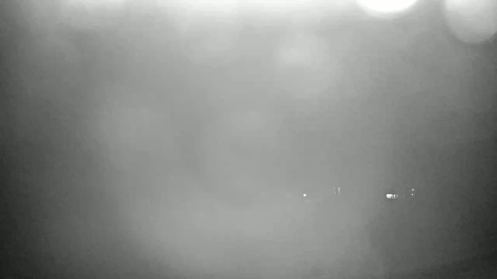 A blurry, hazy image shows a few faint lights in the distance on a foggy night.