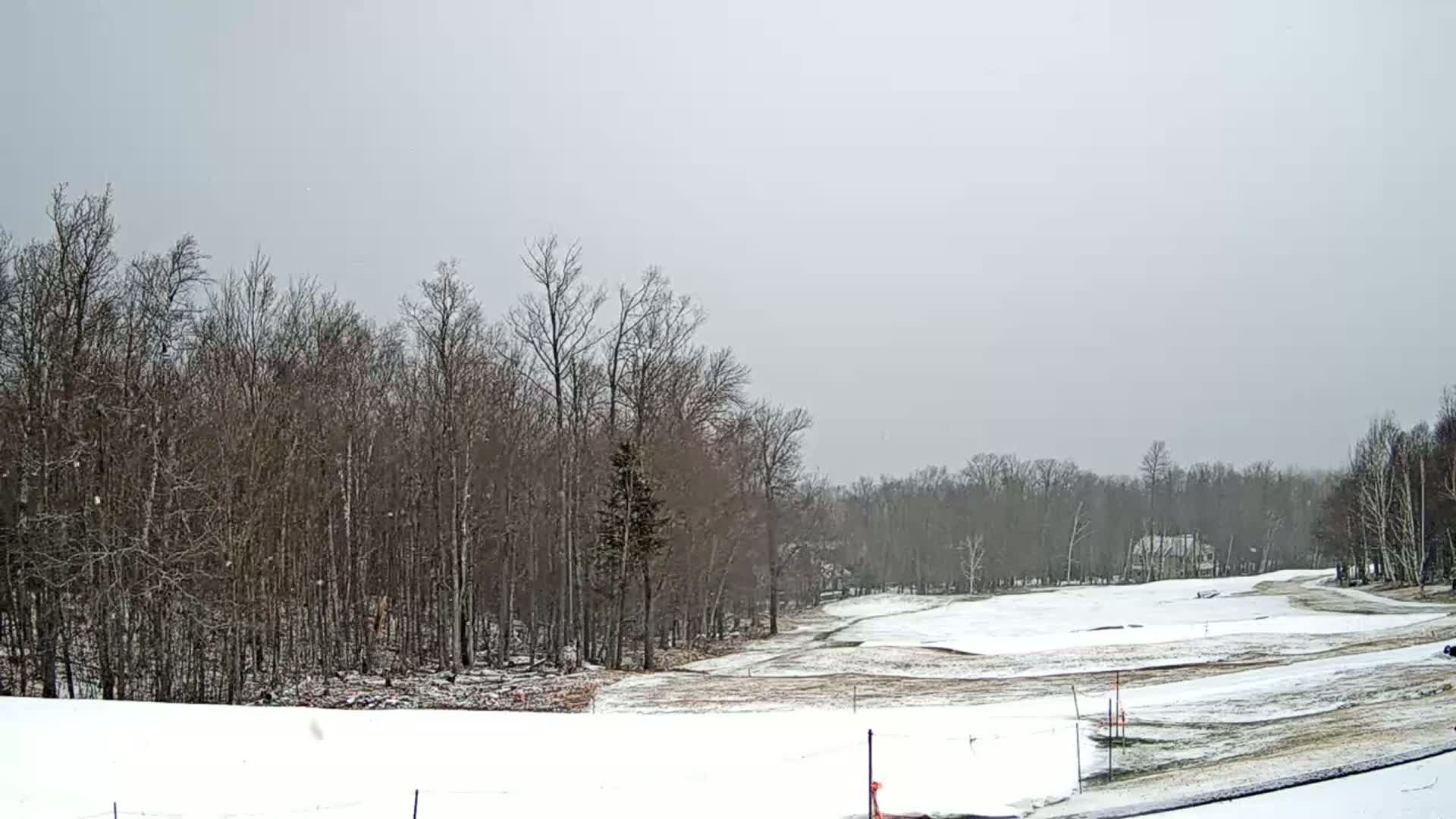 A snow-covered golf course is partially visible, bordered by leafless trees under a gray sky.
