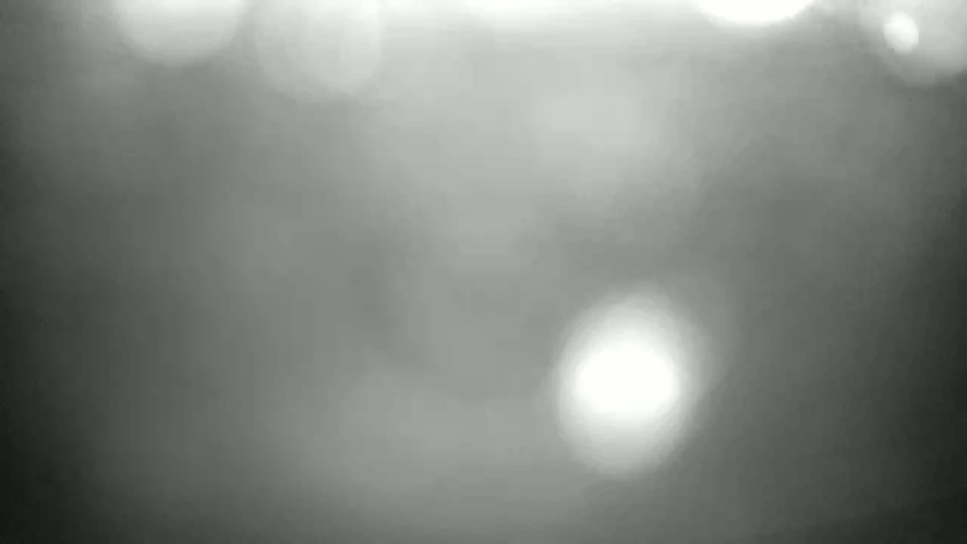 A blurry grayscale image shows out-of-focus bright spots against a dark background.
