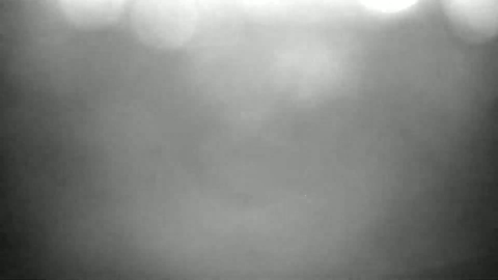 A blurry, grayscale image shows an indistinct, foggy or hazy scene with bright, out-of-focus lights in the upper portion.