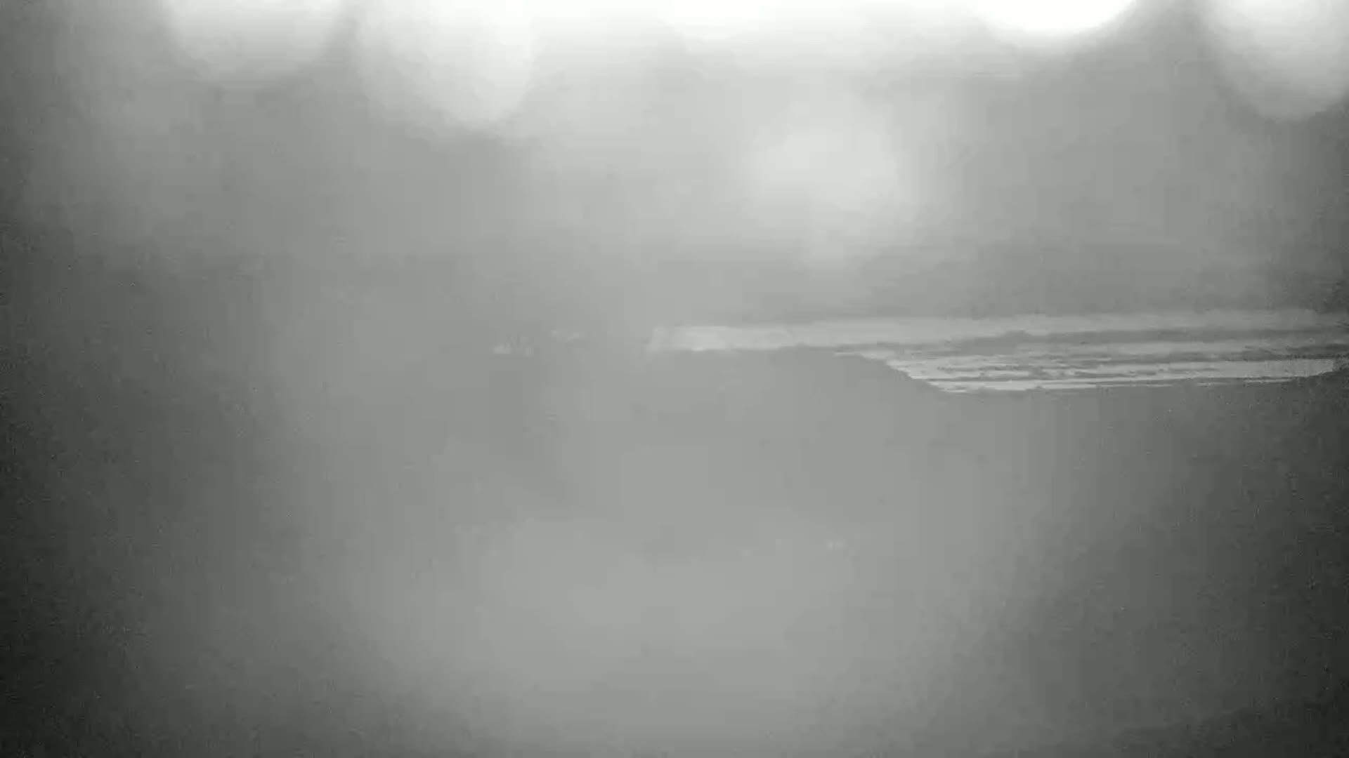 A hazy, overcast day reveals a distant body of water with faint horizontal lines suggesting waves or ripples.