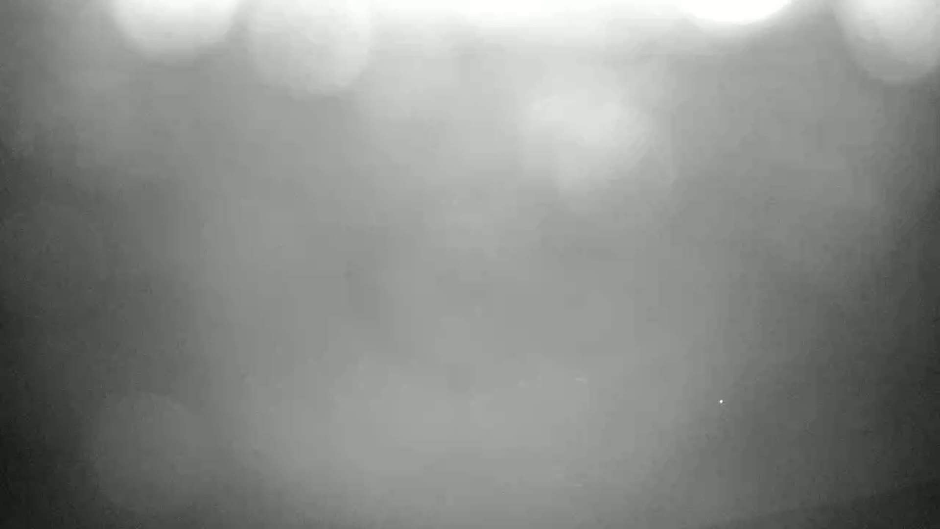 A blurry, out-of-focus image shows a hazy or foggy scene with bright, indistinct lights in the upper portion.