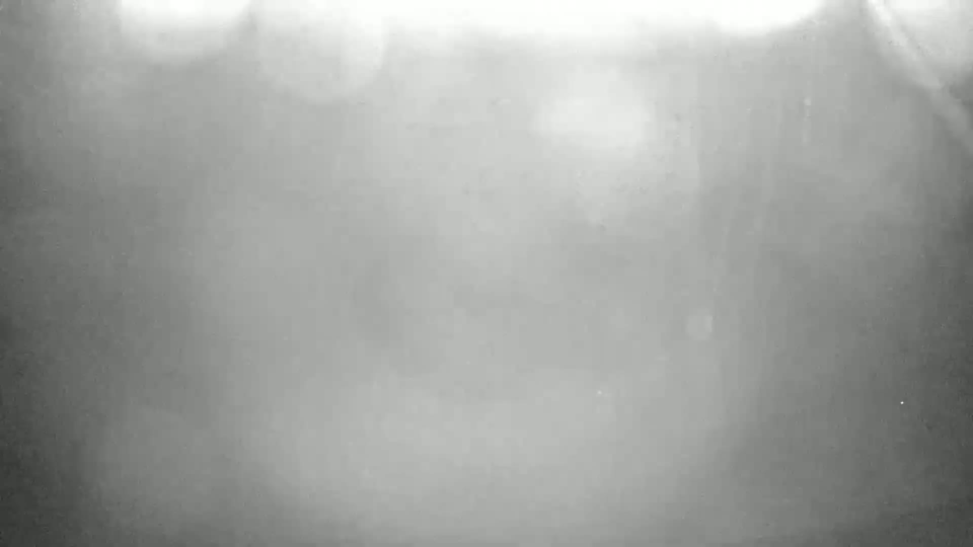 A blurry, grayscale image shows indistinct shapes suggesting buildings in a dense fog.