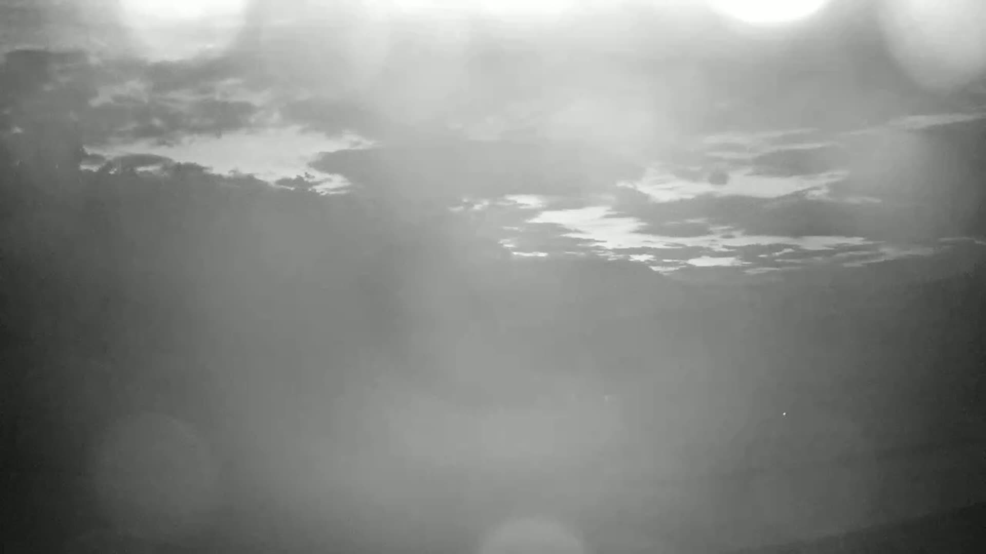 A hazy, overcast sky with a bright area suggesting the sun through the clouds.