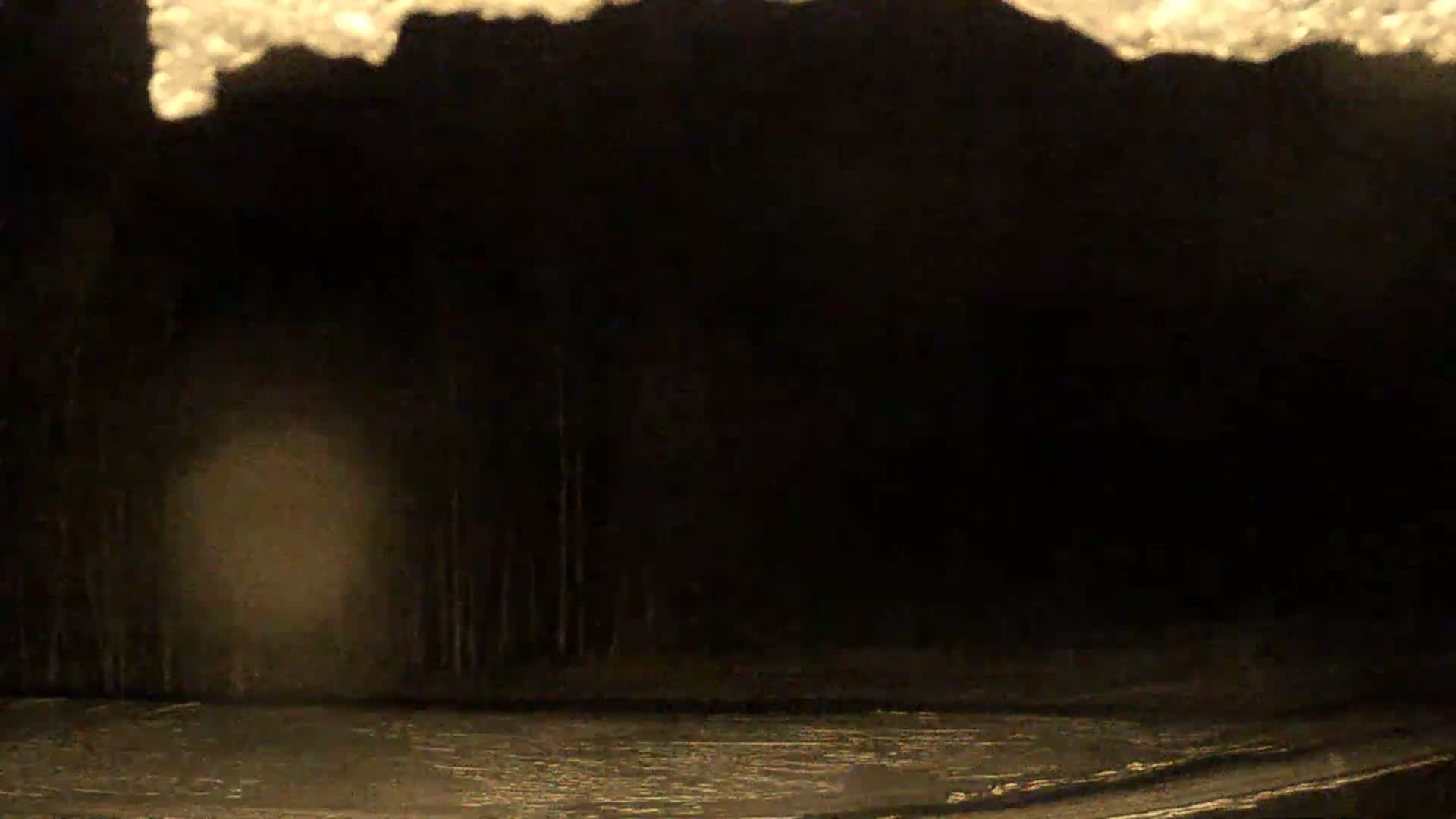 A dark, snowy or foggy night scene reveals a dimly lit, reflective ground surface, possibly a road, with faint trees in the background, a hazy light source on the left, all under an irregular bright area at the top.