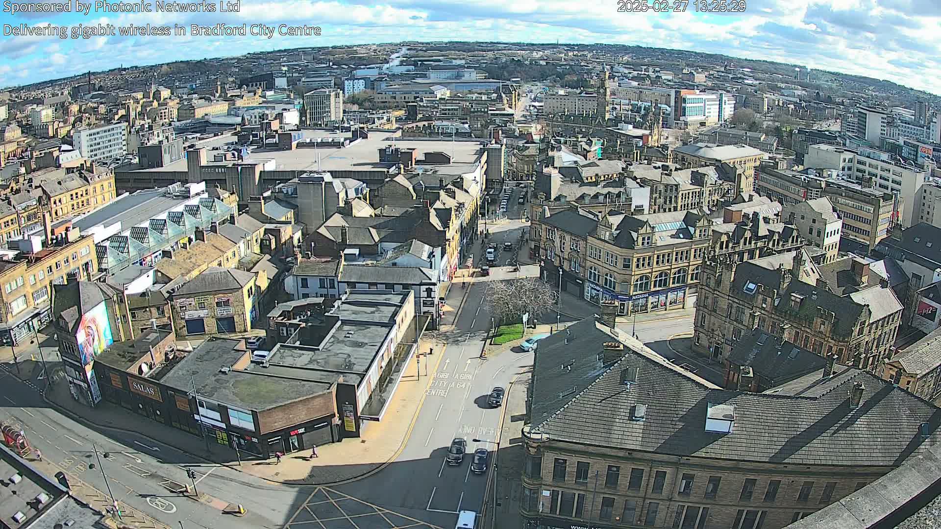 A high-angle, sunny view of a city center with numerous buildings and streets, showing a mix of architectural styles.