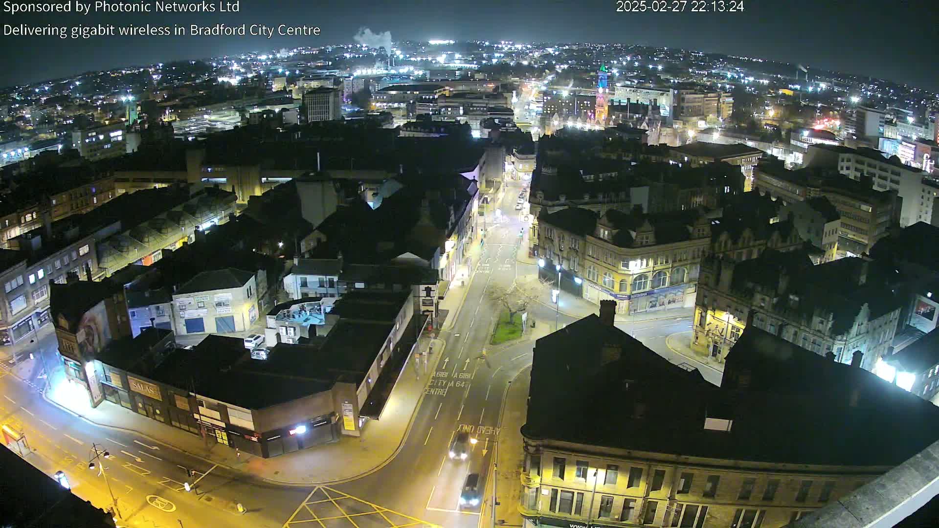 A nighttime aerial view of a city center with illuminated streets and buildings under a clear sky.