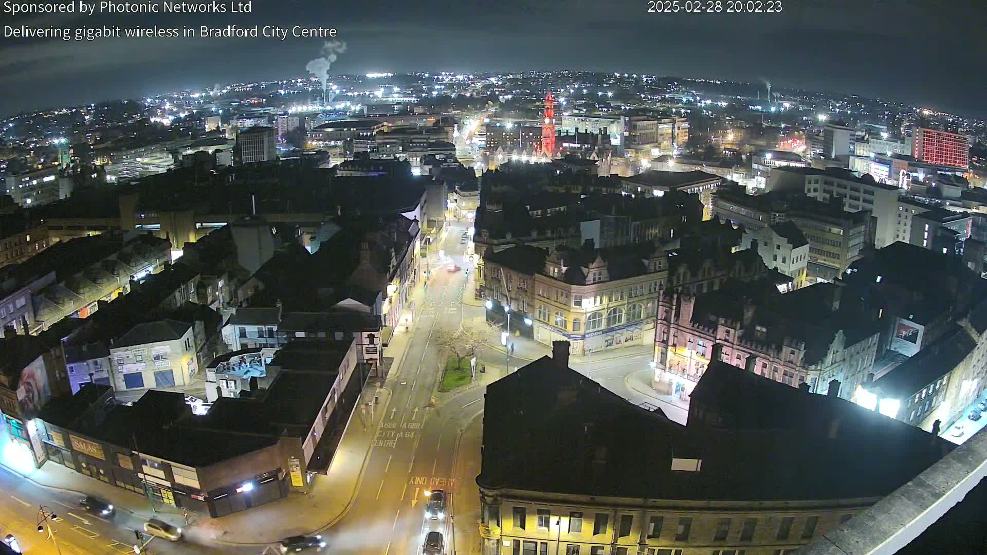 A nighttime aerial view of a city center, showing illuminated buildings and streets with minimal traffic.