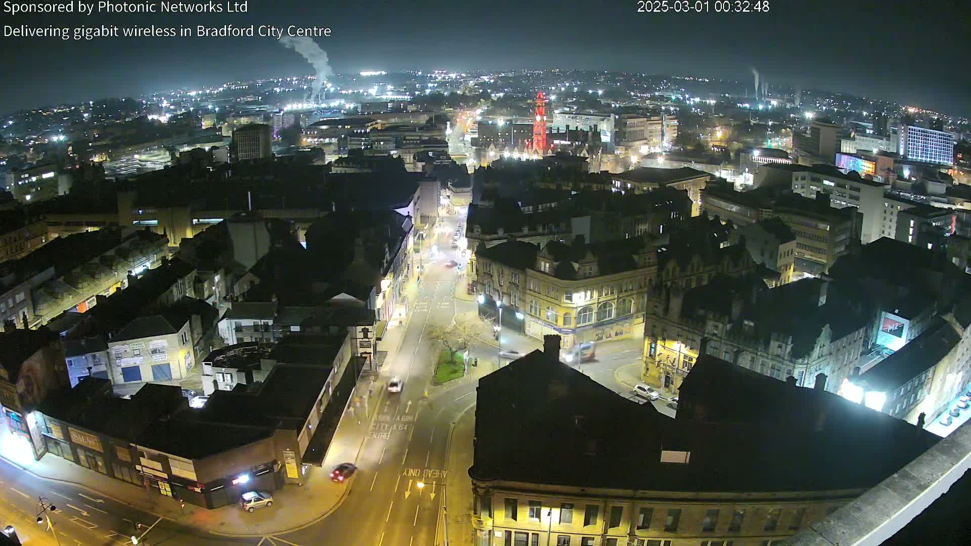 A nighttime aerial view of a city center with illuminated buildings and streets, under a clear sky.