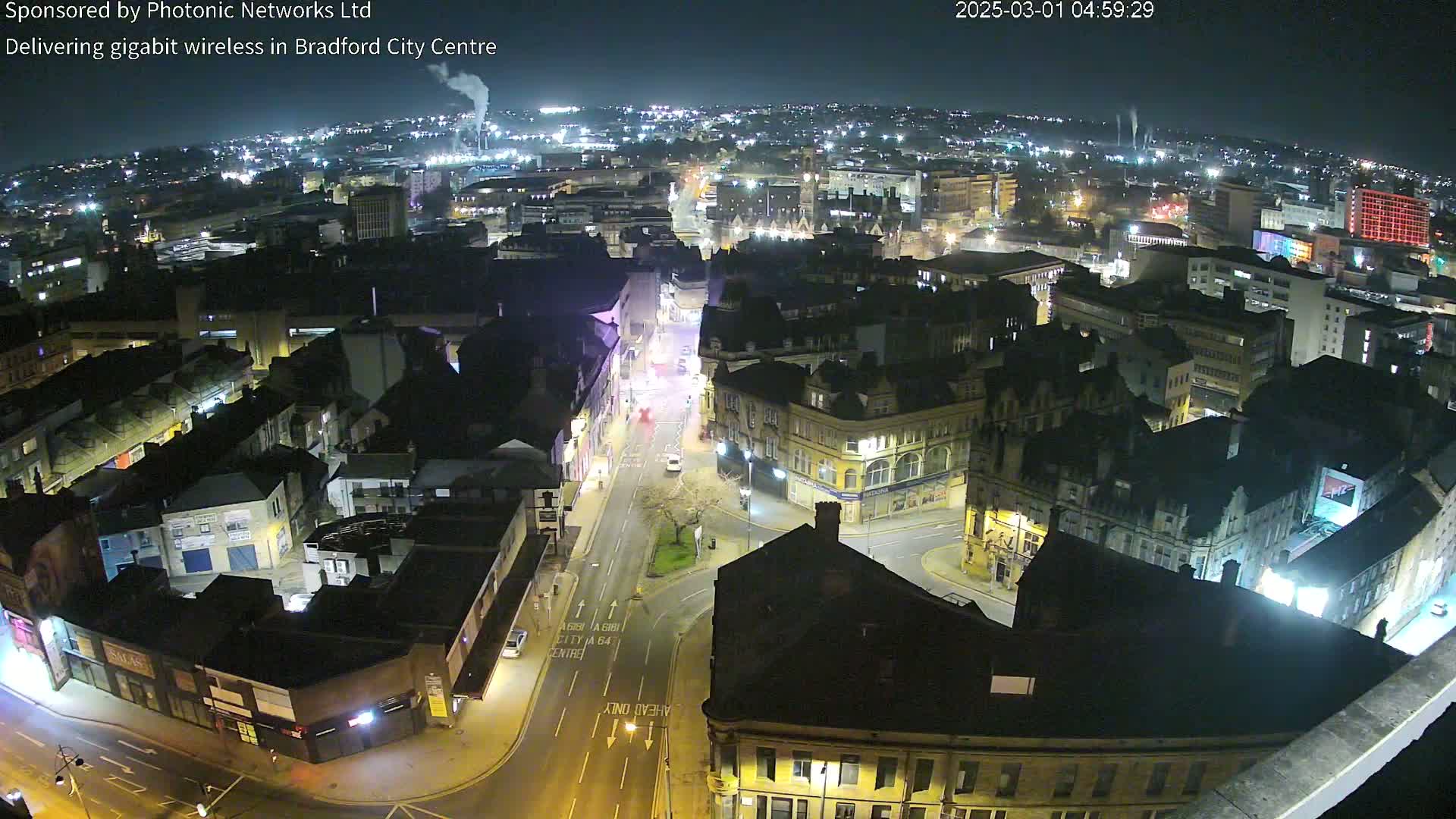A nighttime aerial view of a city, showing illuminated buildings and streets under a clear, dark sky.