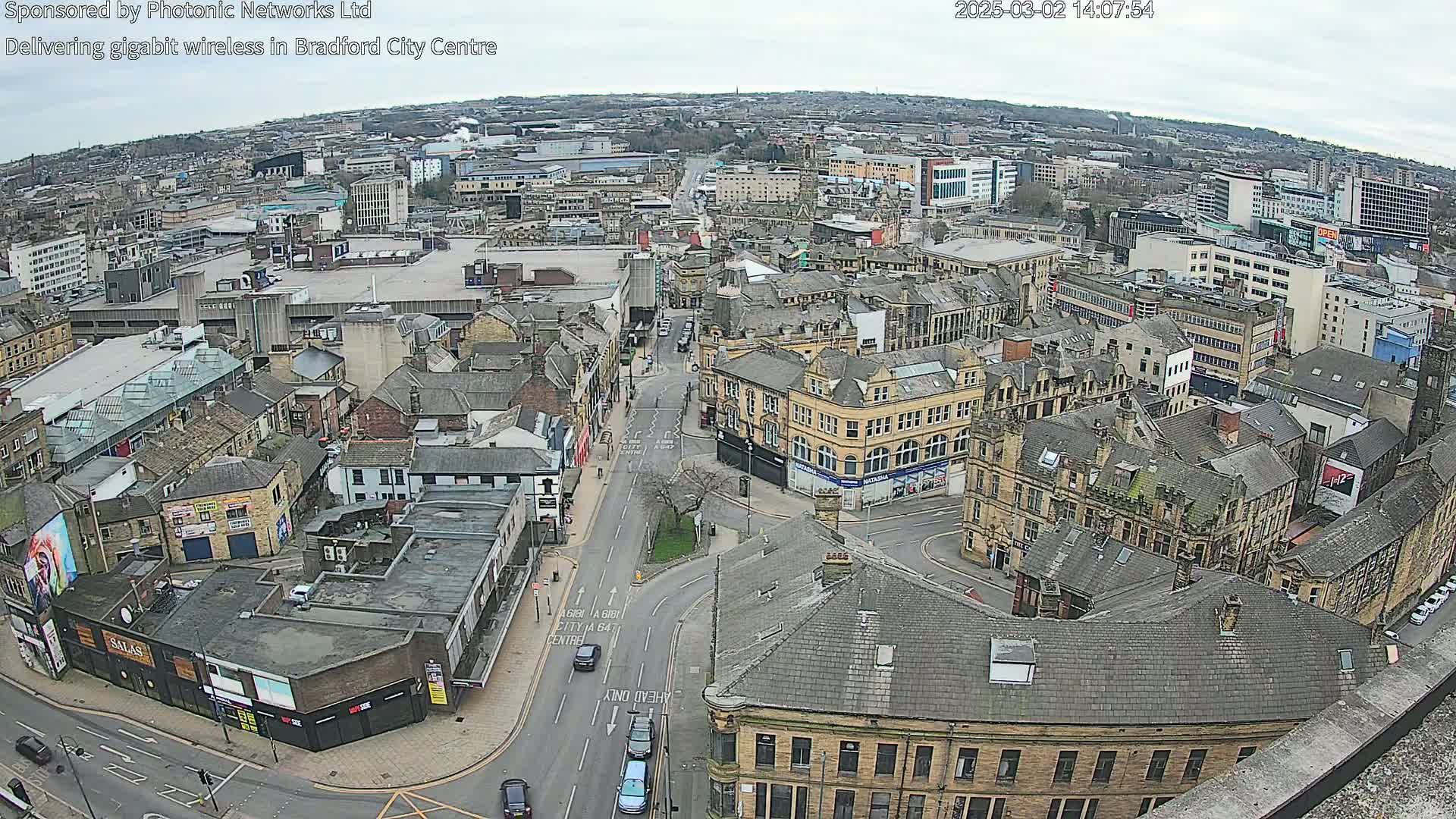 A high-angle view of a city center on an overcast day, showing numerous buildings and streets with sparse traffic.