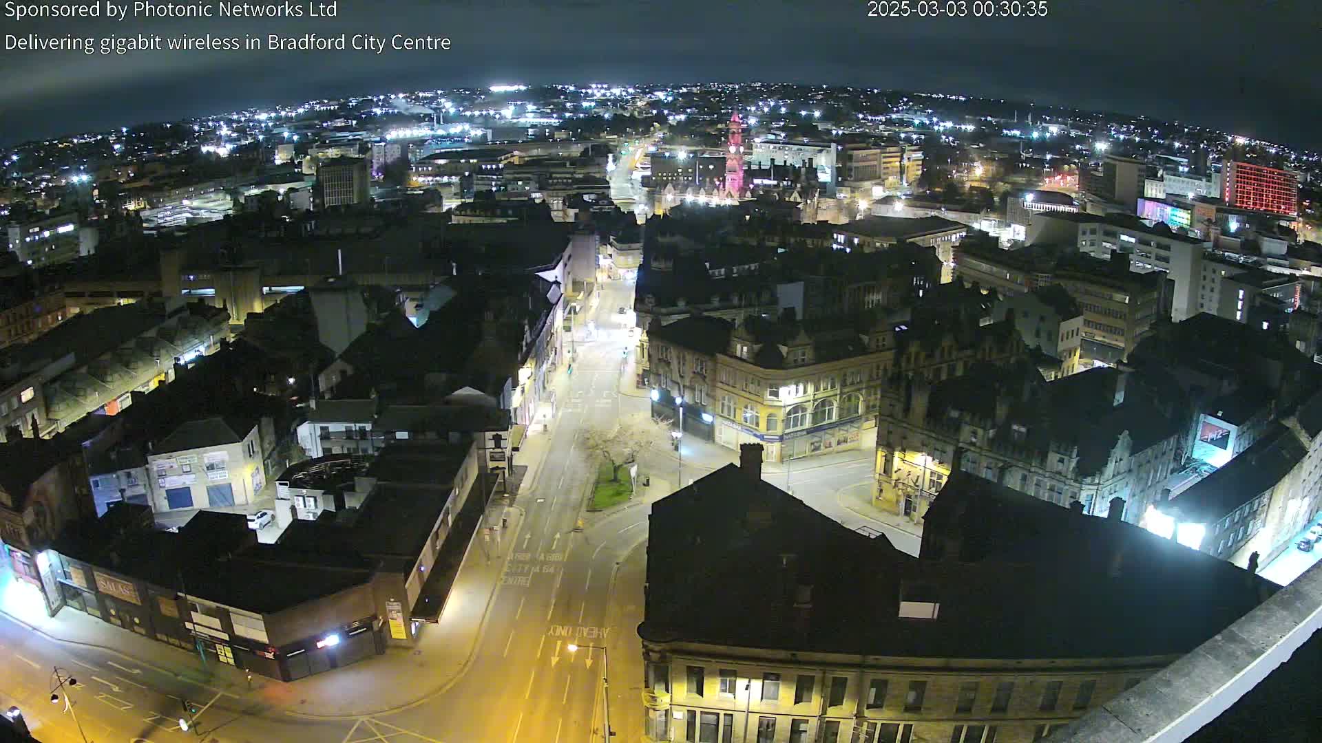 A nighttime, high-angle view of a city center with illuminated buildings and streets.