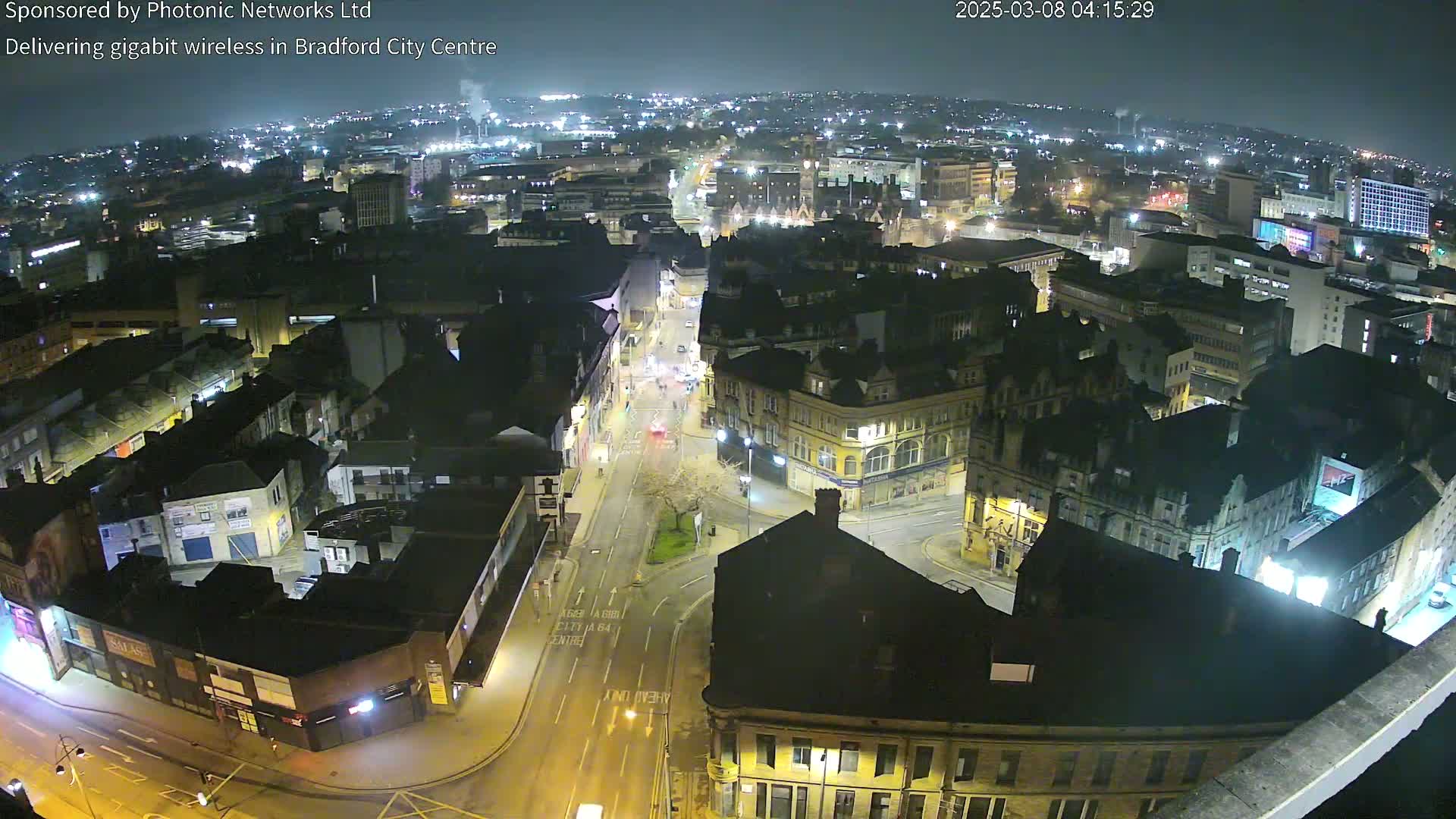 A nighttime aerial view of a city center with illuminated buildings and streets.