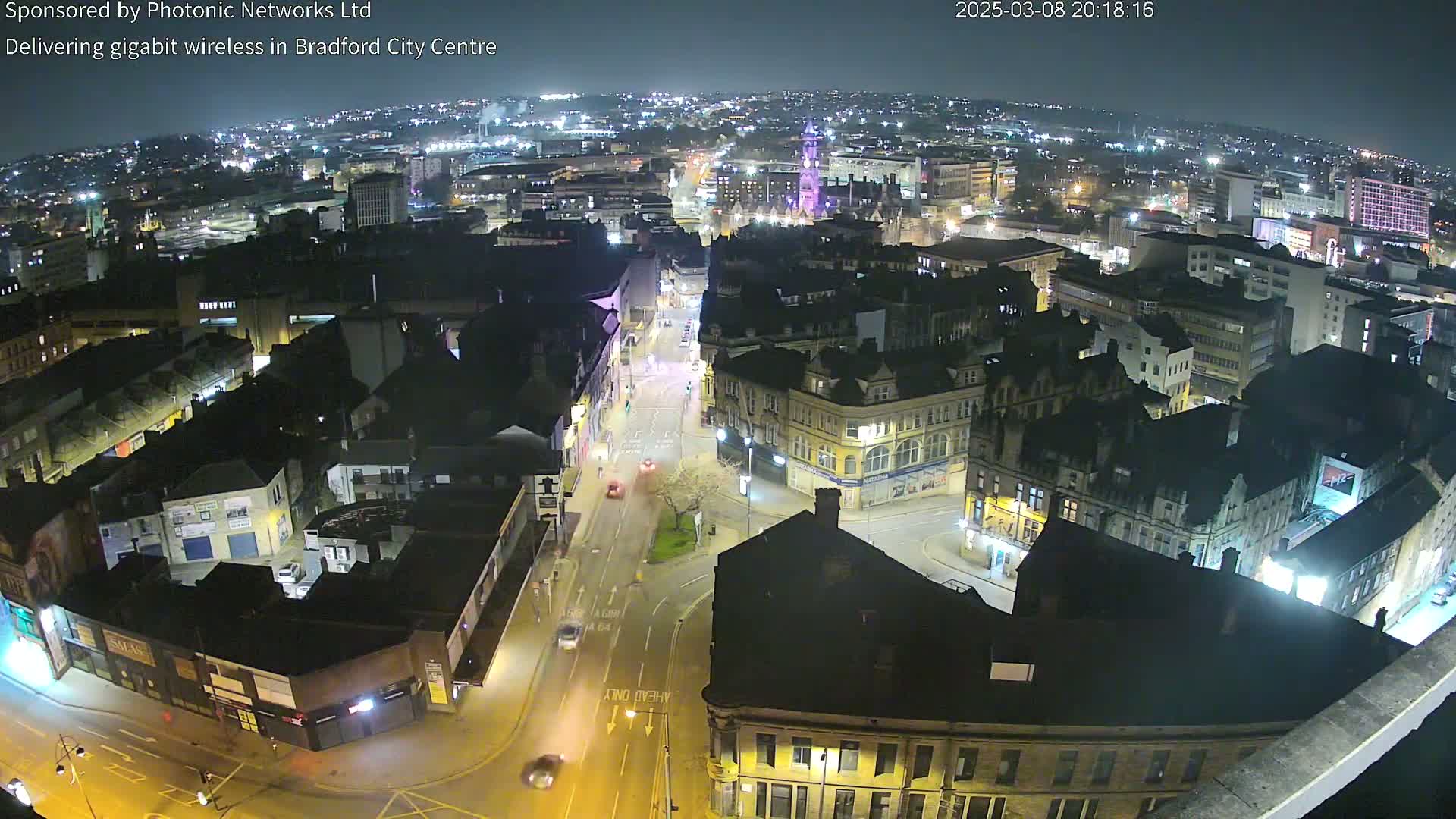 A nighttime aerial view of a city center, showing illuminated streets and buildings under a clear, dark sky.