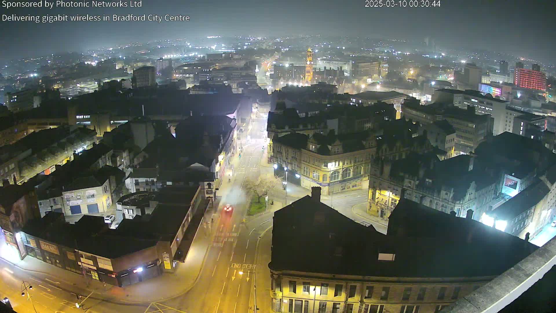 A nighttime aerial view of a city's illuminated streets and buildings under hazy or foggy conditions.