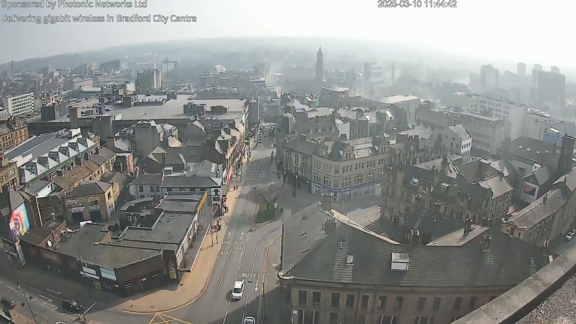 A hazy, high-angle view of a city center, showing numerous buildings and streets with sparse traffic.