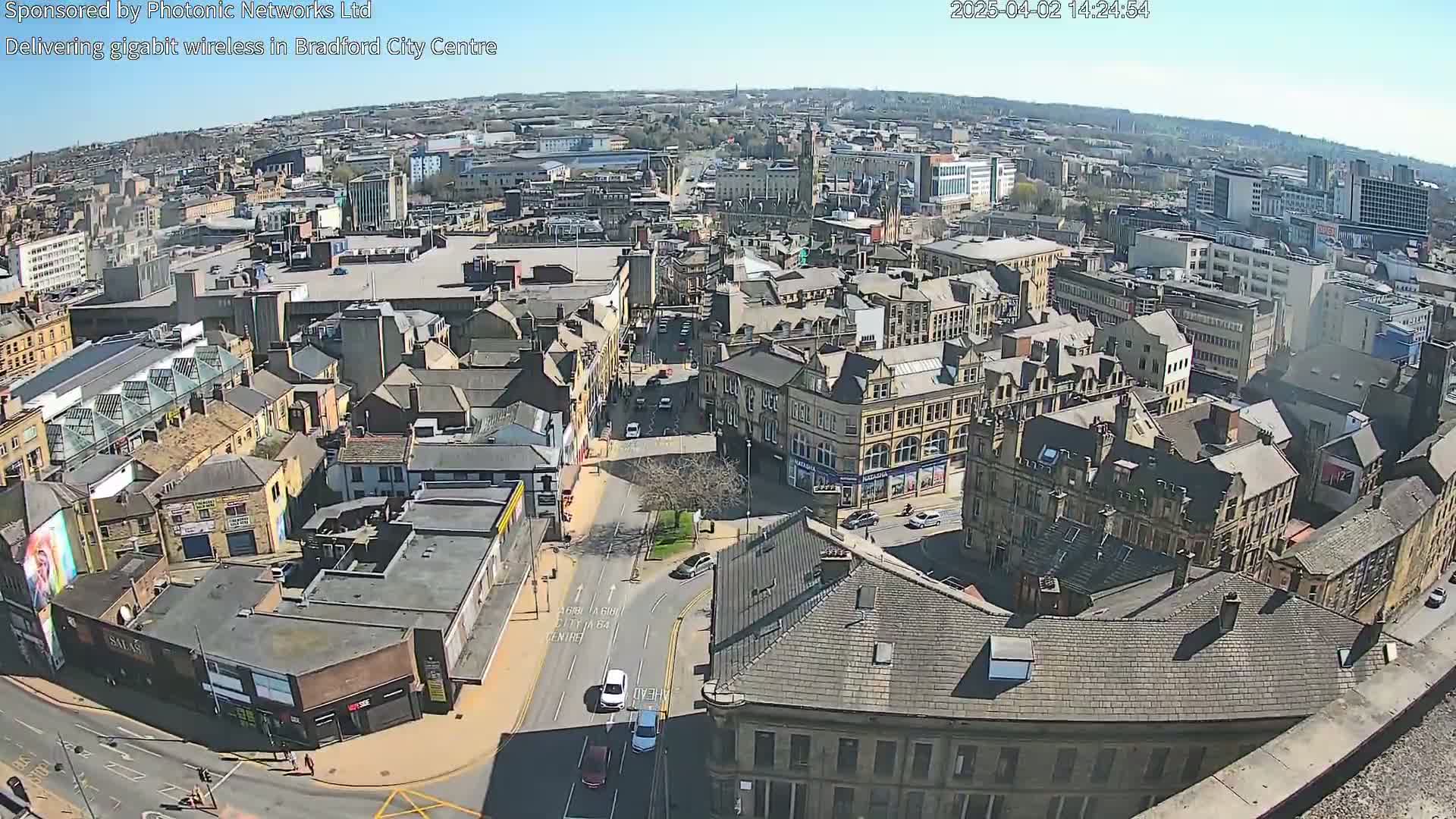 A high-angle, sunny view of a city center with many buildings and streets, showing a mix of architectural styles.
