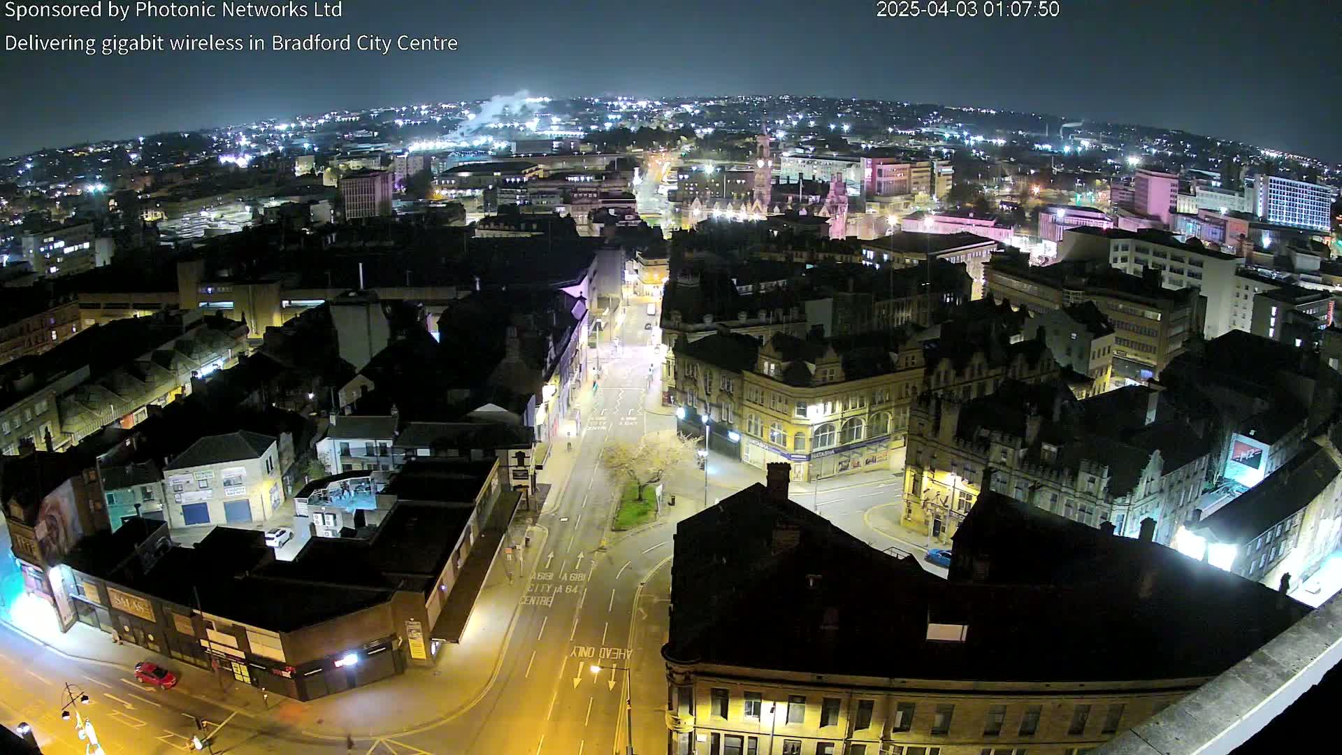 A nighttime aerial view of a city center with illuminated streets and buildings.