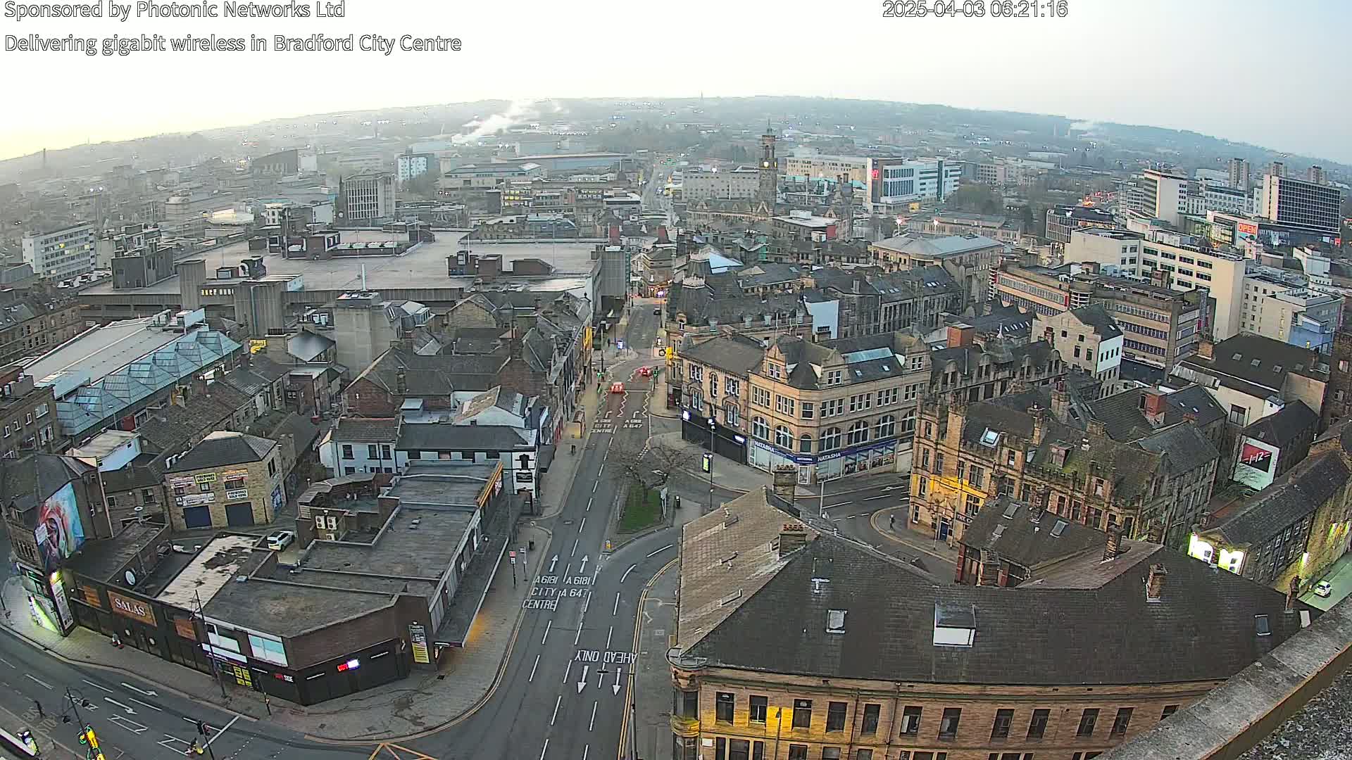 A high-angle, twilight view of a city center, showing many buildings and streets with minimal traffic.
