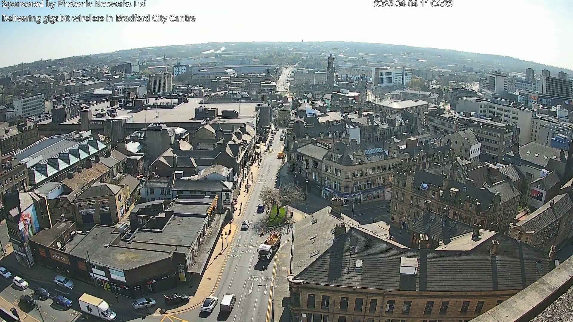 A high-angle, long shot of a city on a sunny day, showing many buildings and streets with sparse traffic.