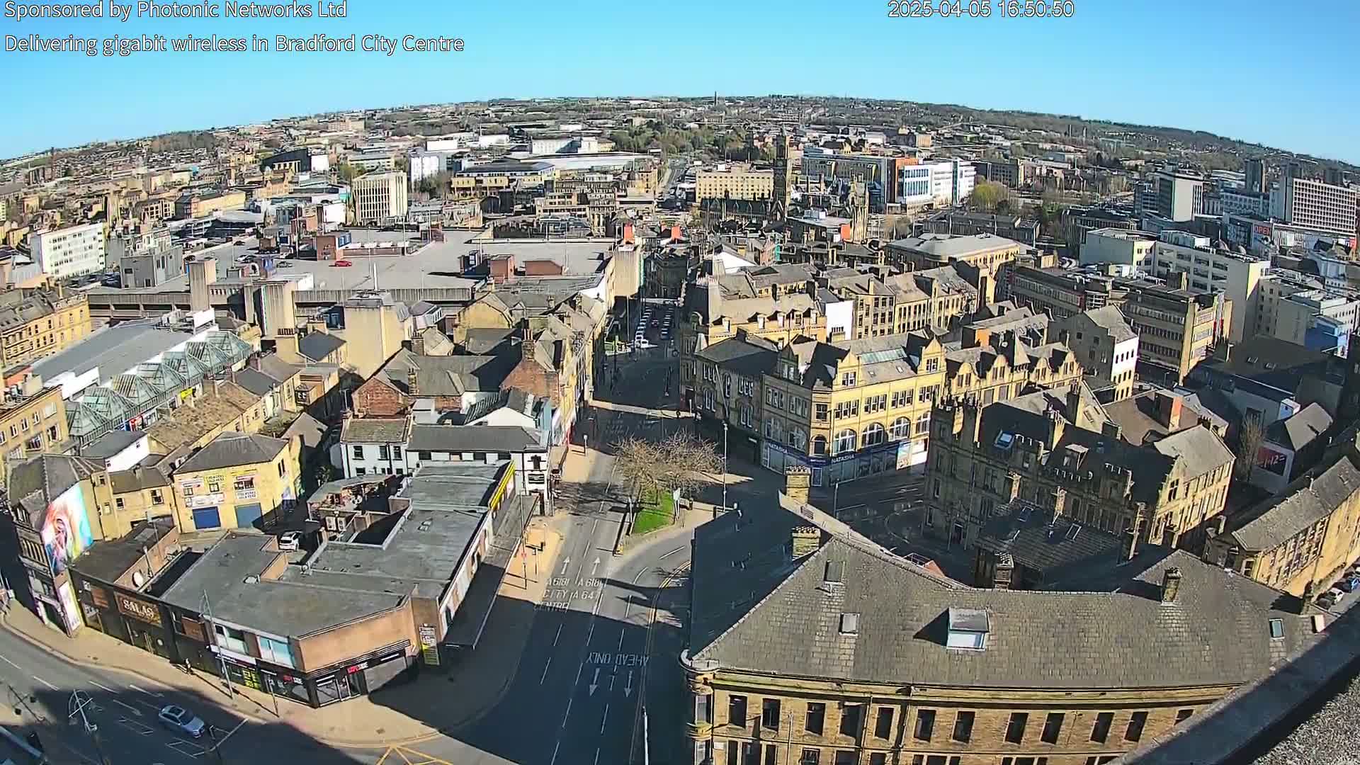A high-angle, sunny view of a city center with many closely packed buildings, showing streets and a mix of architectural styles.