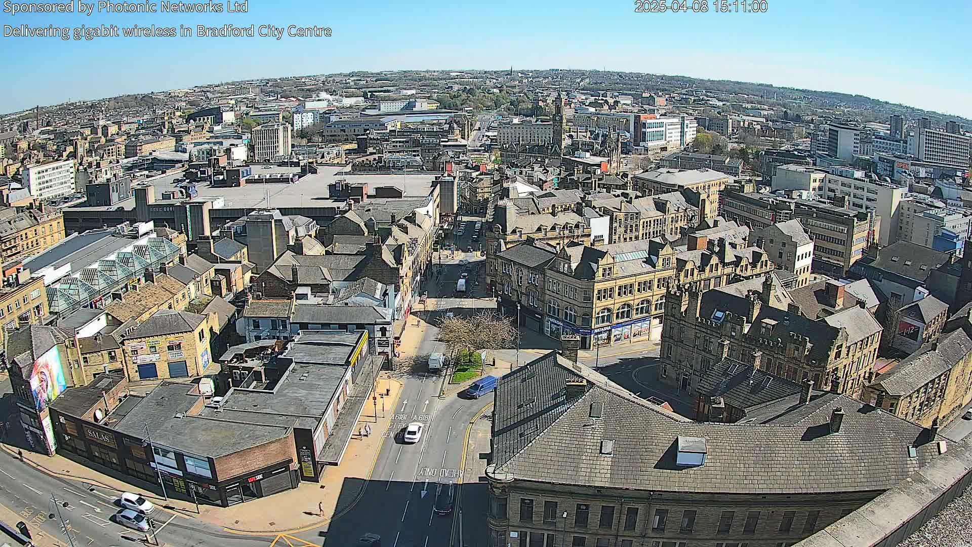 A high-angle, sunny-day view of a city center, showing many stone buildings and streets with sparse traffic.