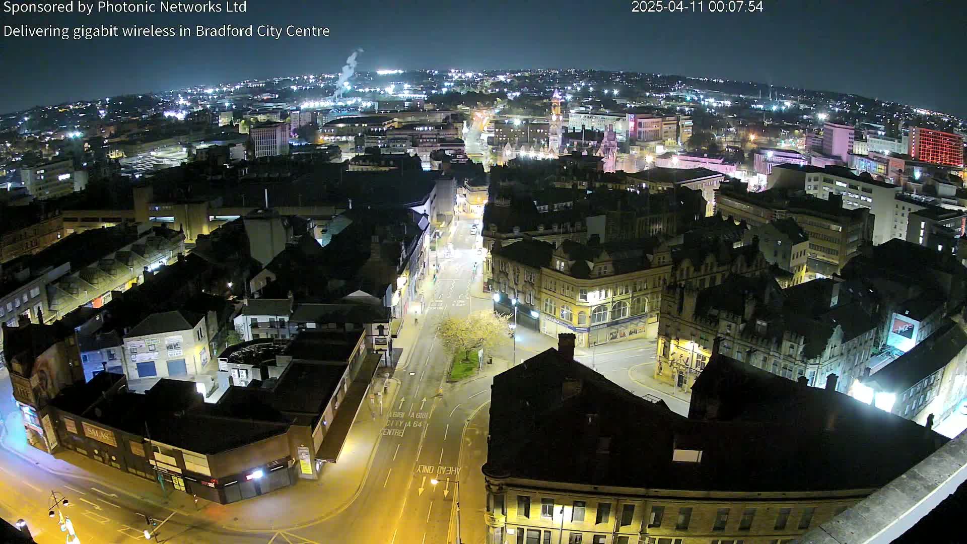 A nighttime, high-angle view of a city center, showing illuminated buildings and streets.