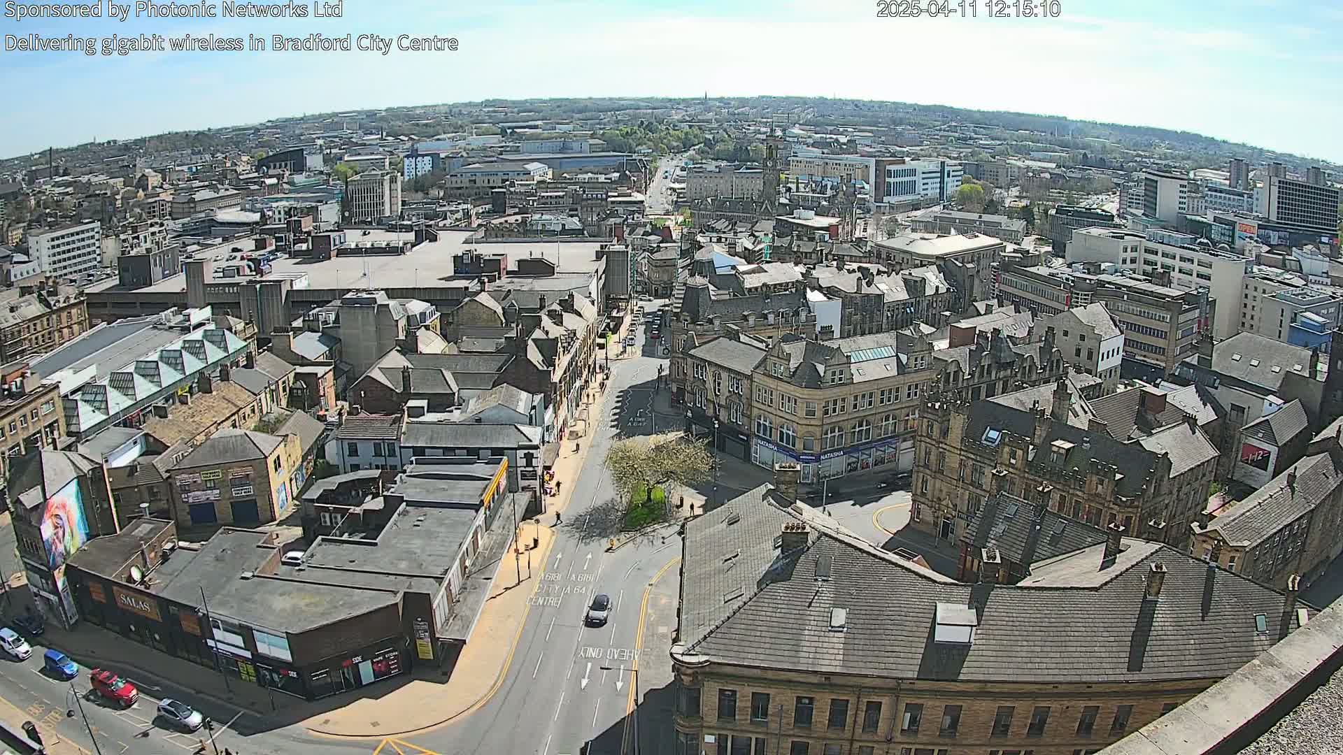 A high-angle, sunny-day view of a city center, showing many buildings and streets with light traffic.
