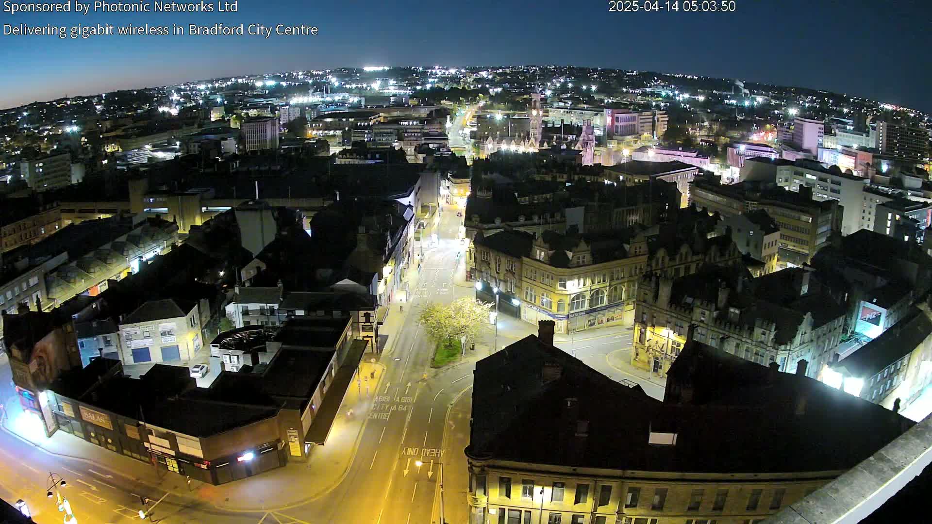 A nighttime, high-angle view of a city center, showing many illuminated buildings and streets.