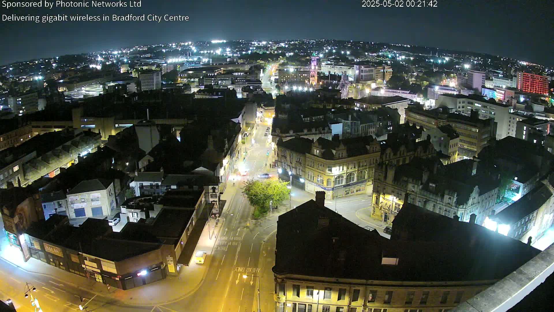 A nighttime aerial view of a city center with illuminated streets and buildings.