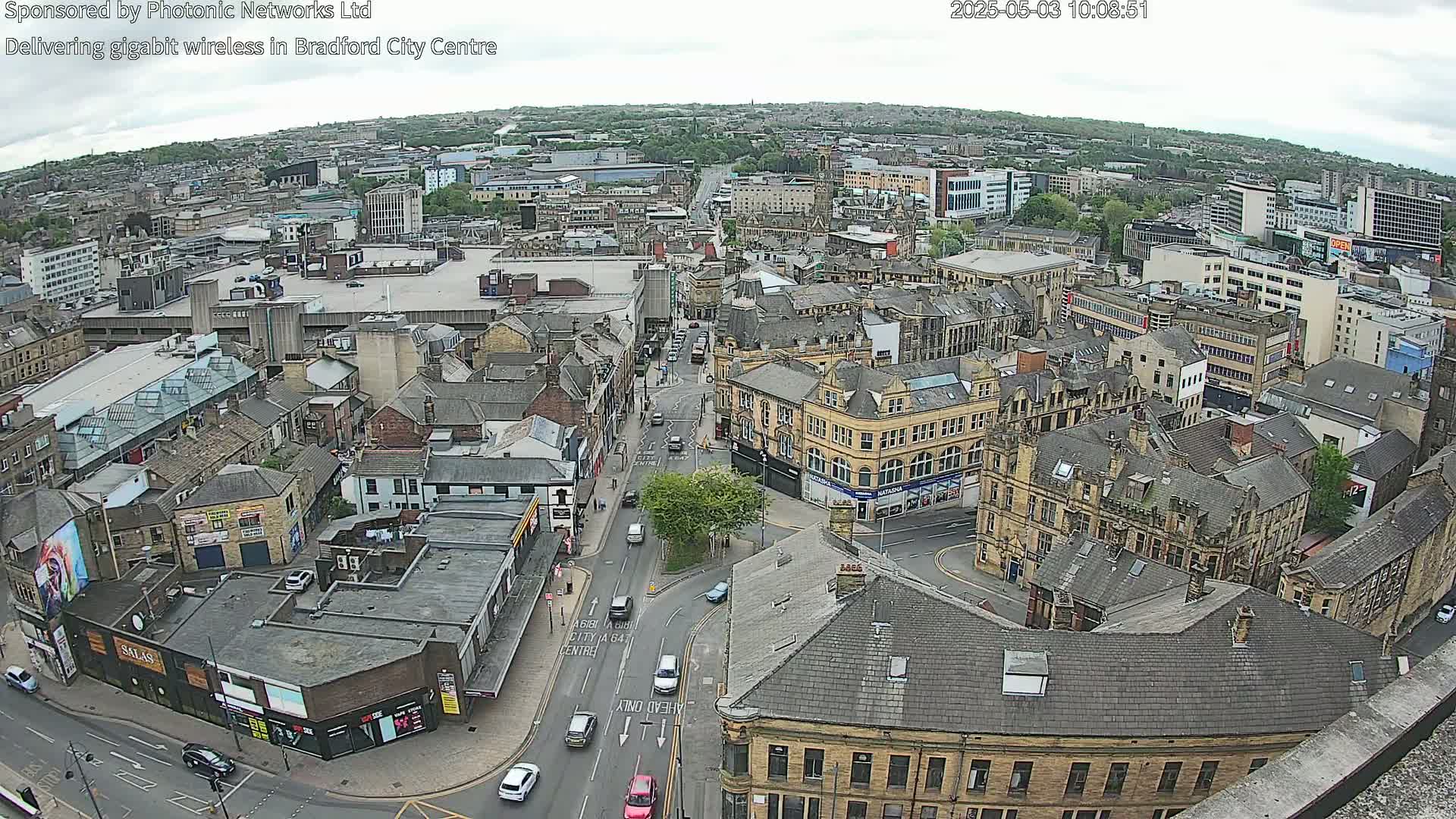 A high-angle view of a city center on an overcast day, showing a dense collection of buildings and streets with cars.