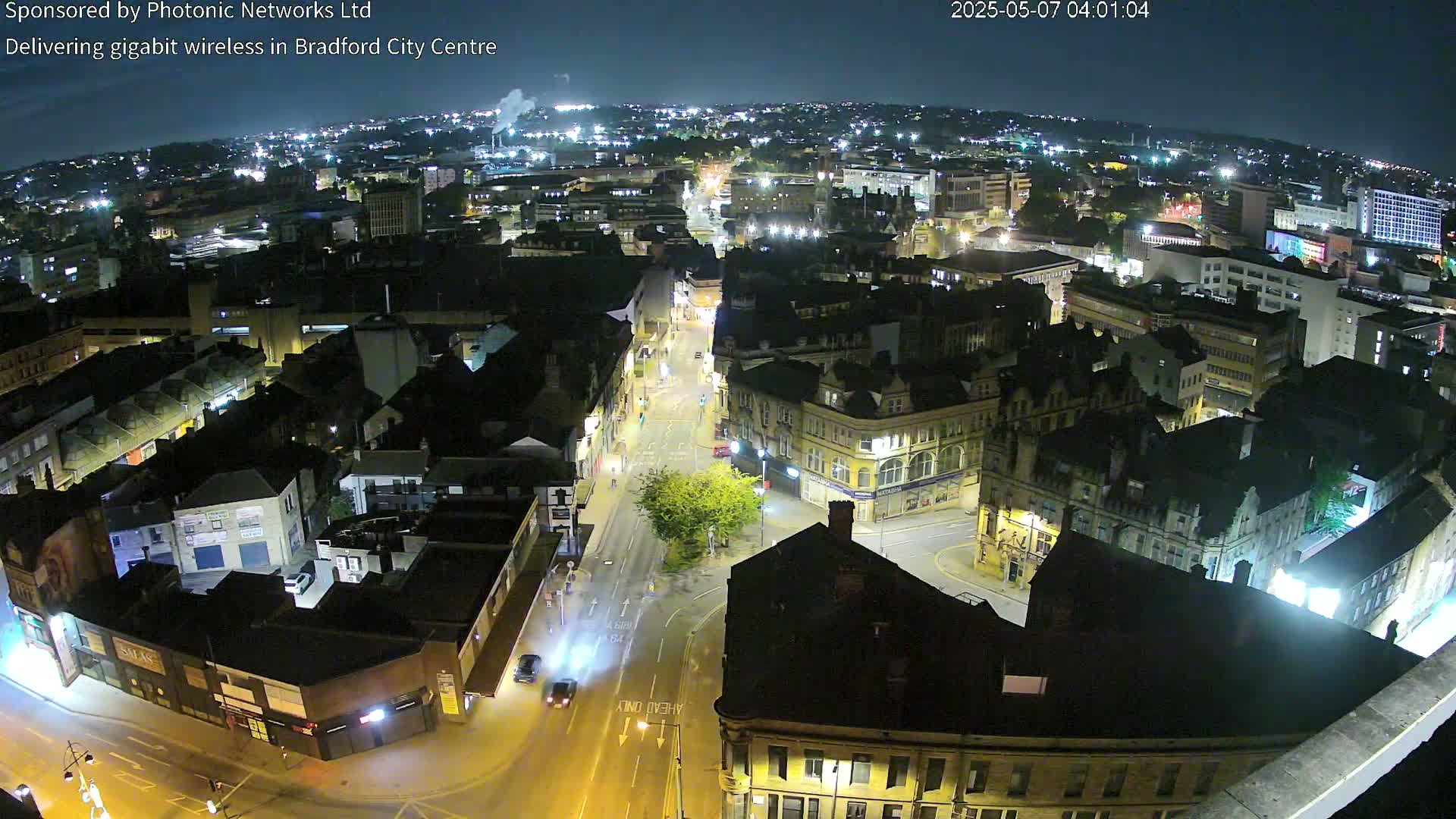 A nighttime aerial view shows a city center with illuminated streets and buildings.