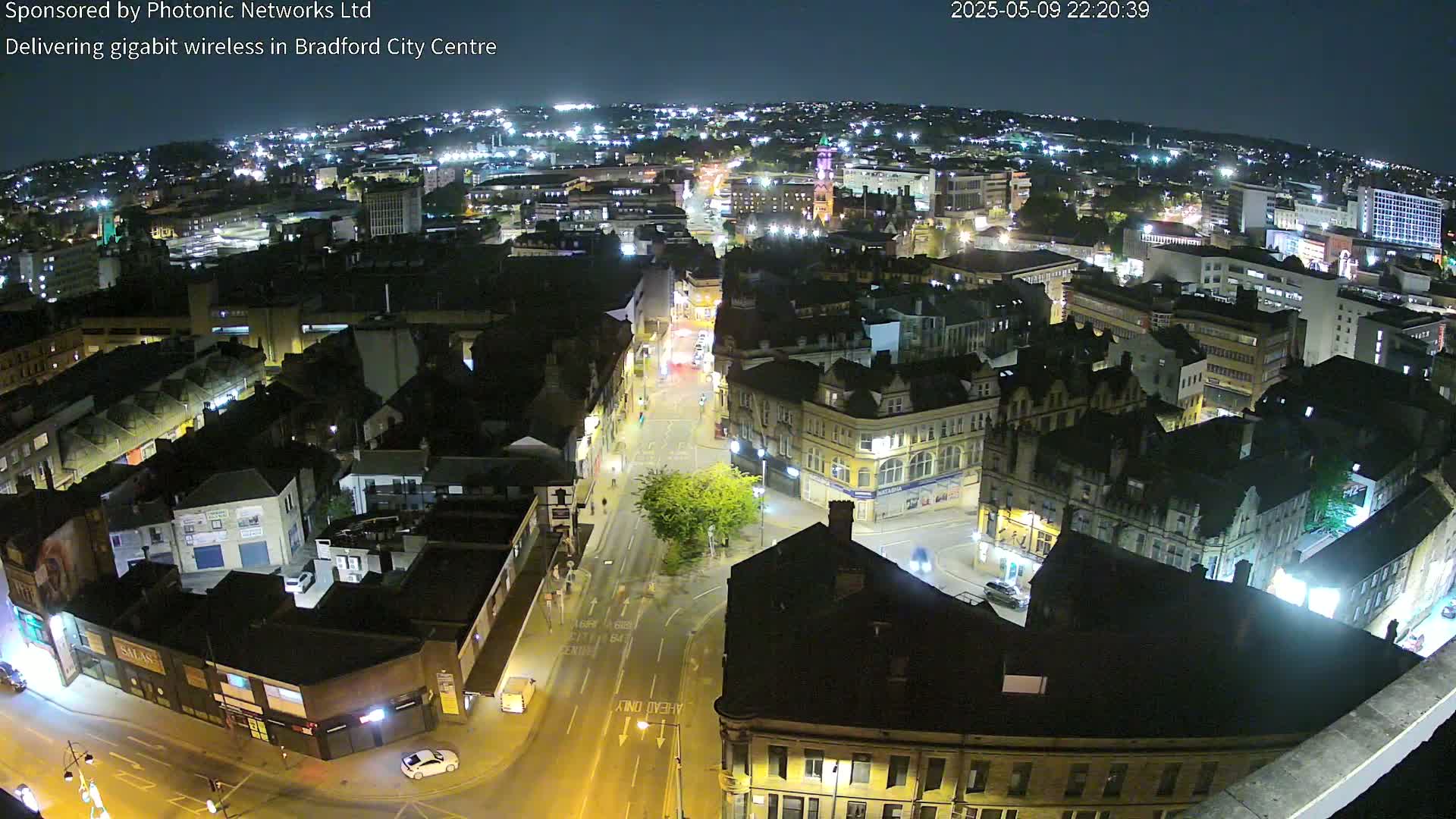 A nighttime aerial view of a city center, showing illuminated buildings and streets with minimal traffic.