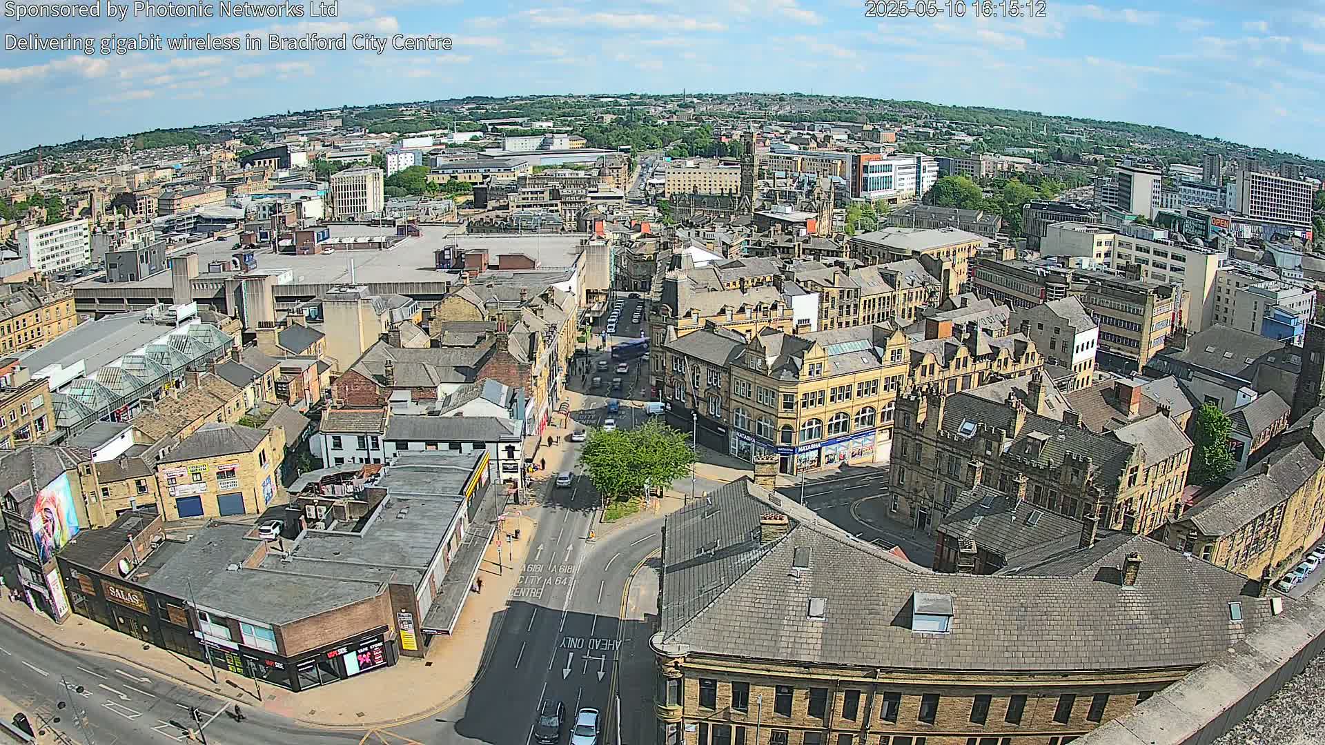 A high-angle, sunny view of a city center with numerous buildings and streets, showing a mix of architectural styles.