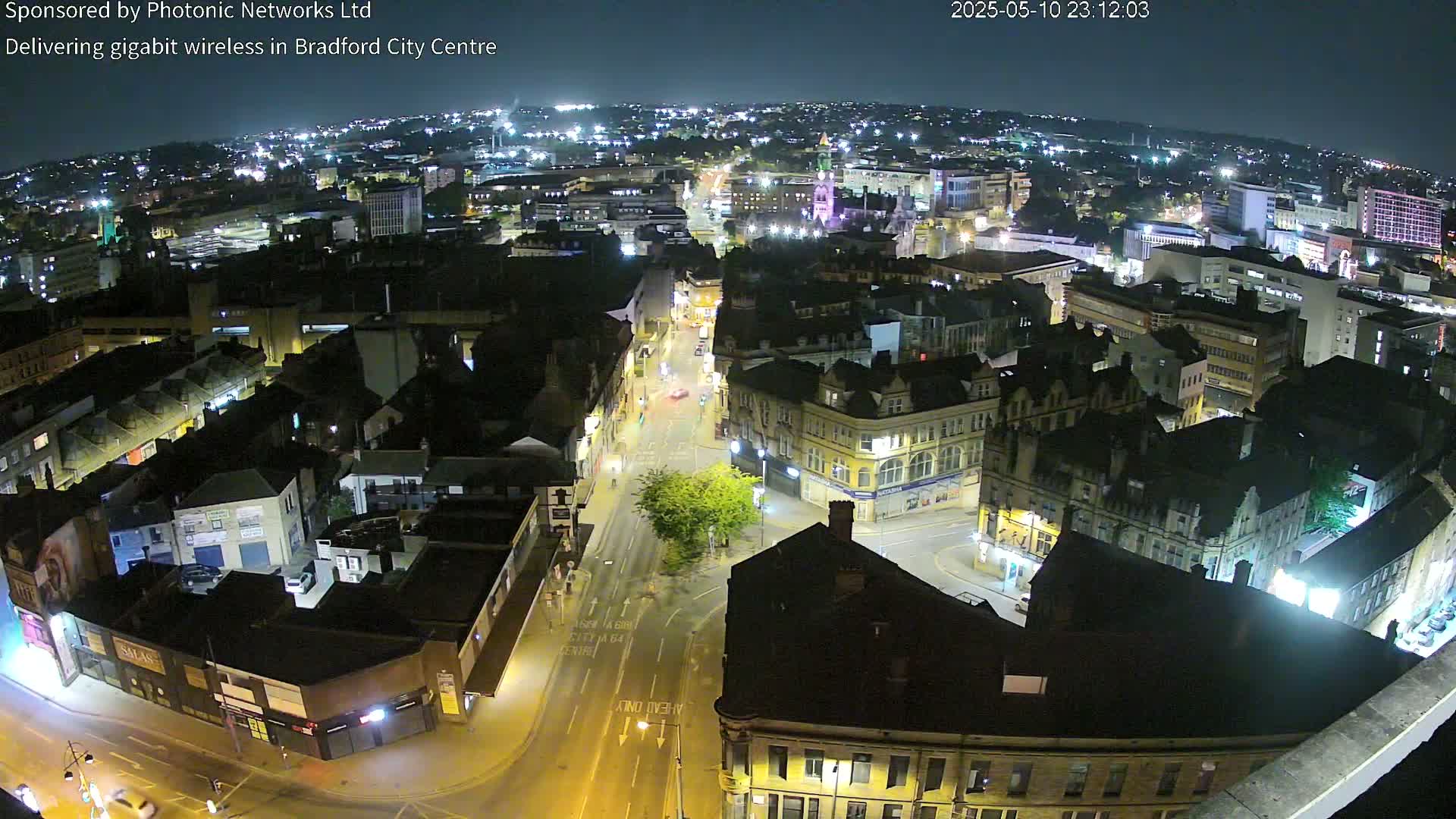 A nighttime aerial view of a city center with illuminated streets and buildings, under a clear dark sky.