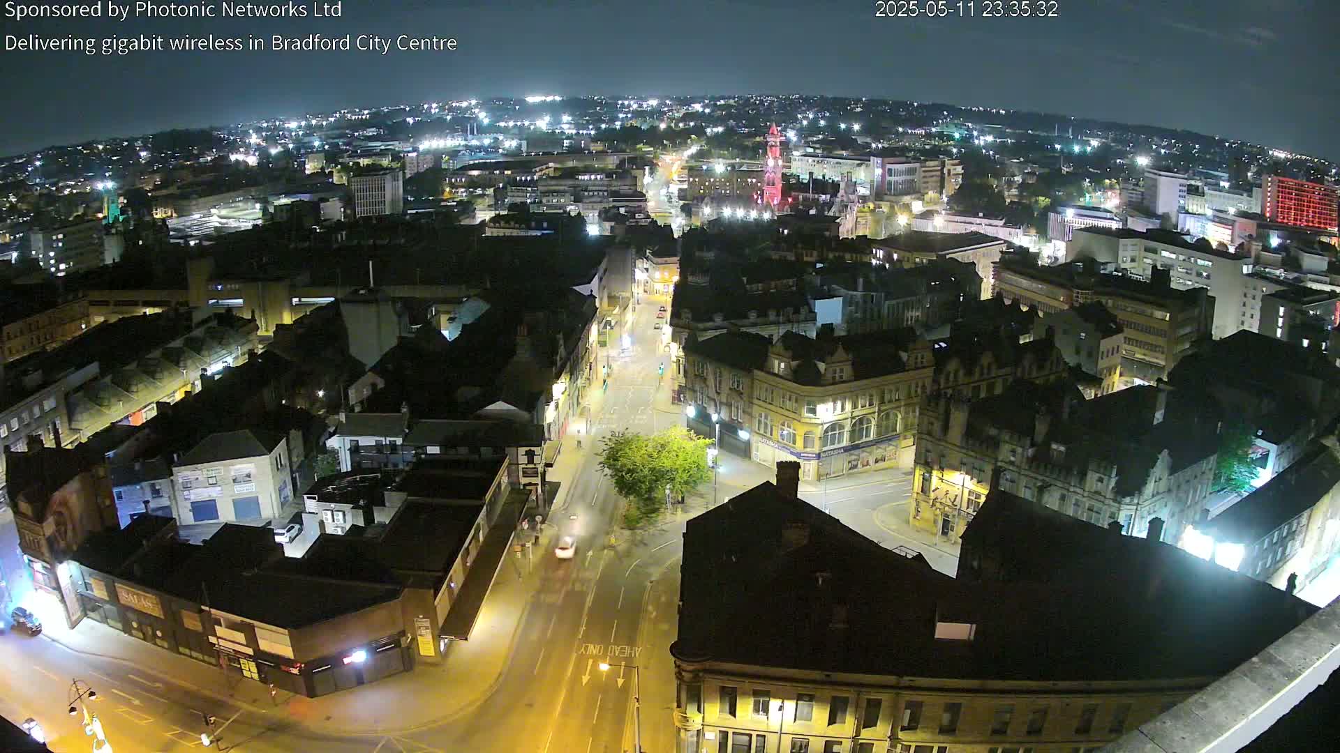 A nighttime aerial view of a city center, showing illuminated streets and buildings under a clear sky.