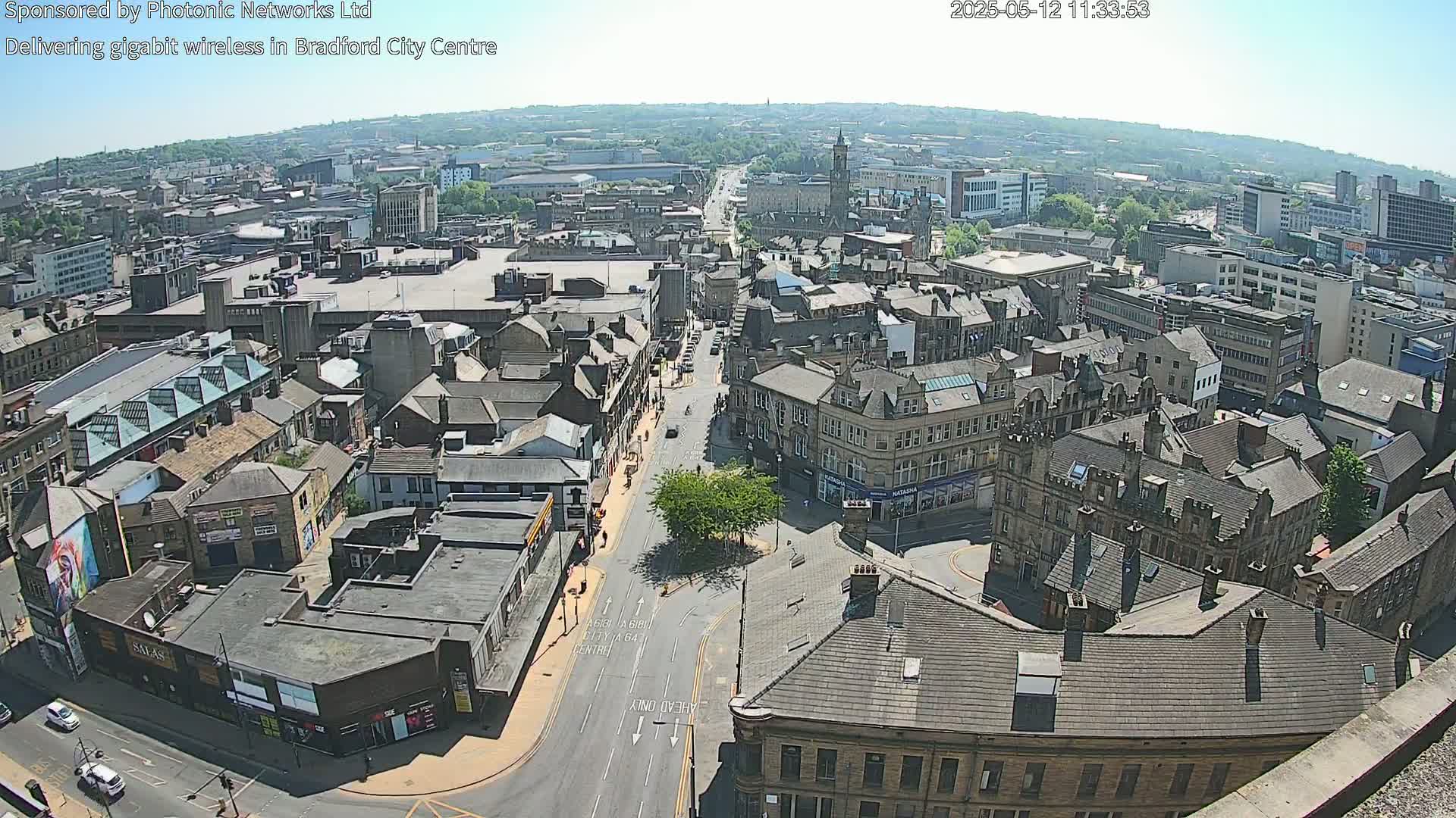 A high-angle, sunny view of a city center with many buildings and a road, showing a clear day.