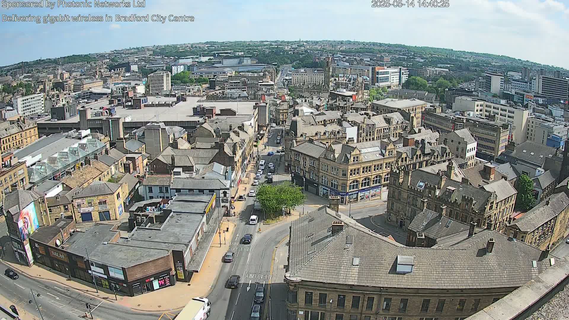 A high-angle, long shot of a city on a sunny day, showing a dense collection of buildings and streets with cars.