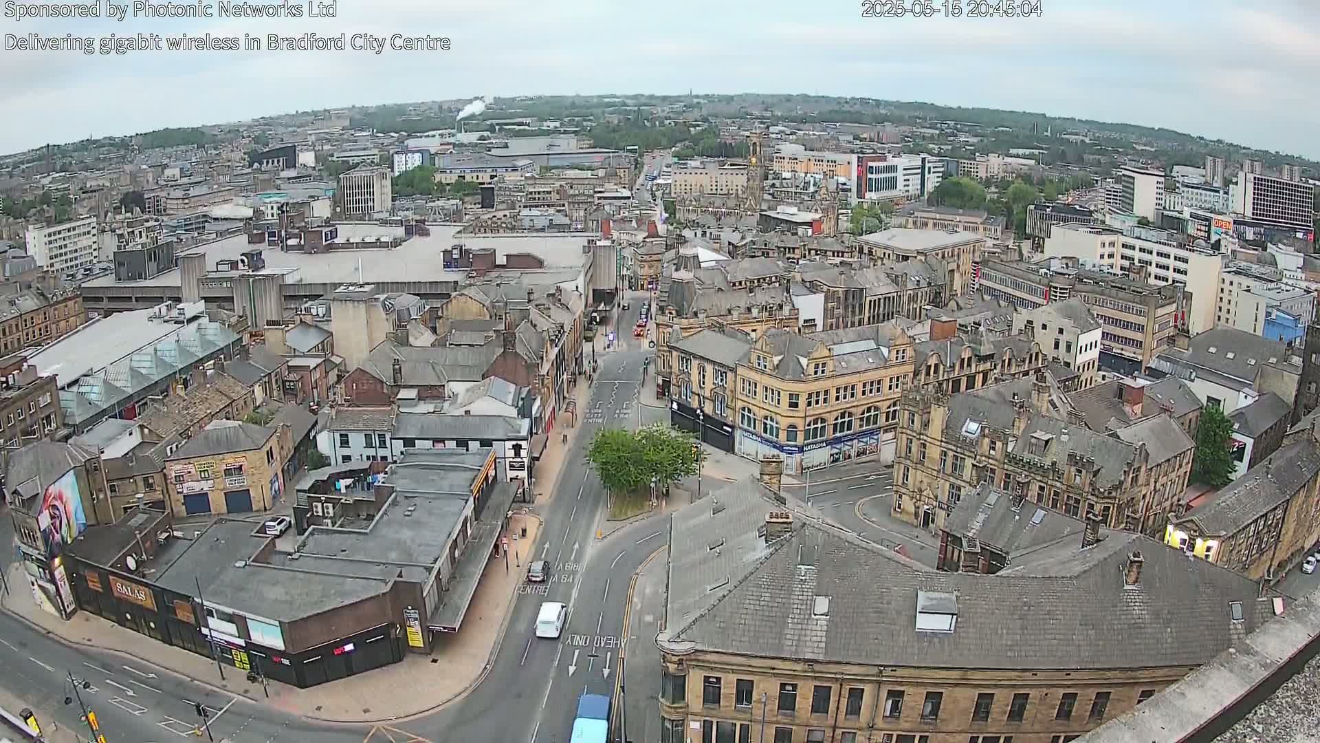 An aerial view of a city center on an overcast day, showing numerous buildings and streets, with some cars visible on the roads.
