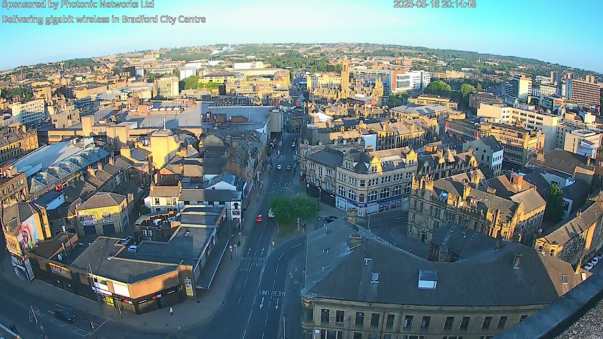 An aerial view of a city center with numerous buildings under a clear, sunny sky.