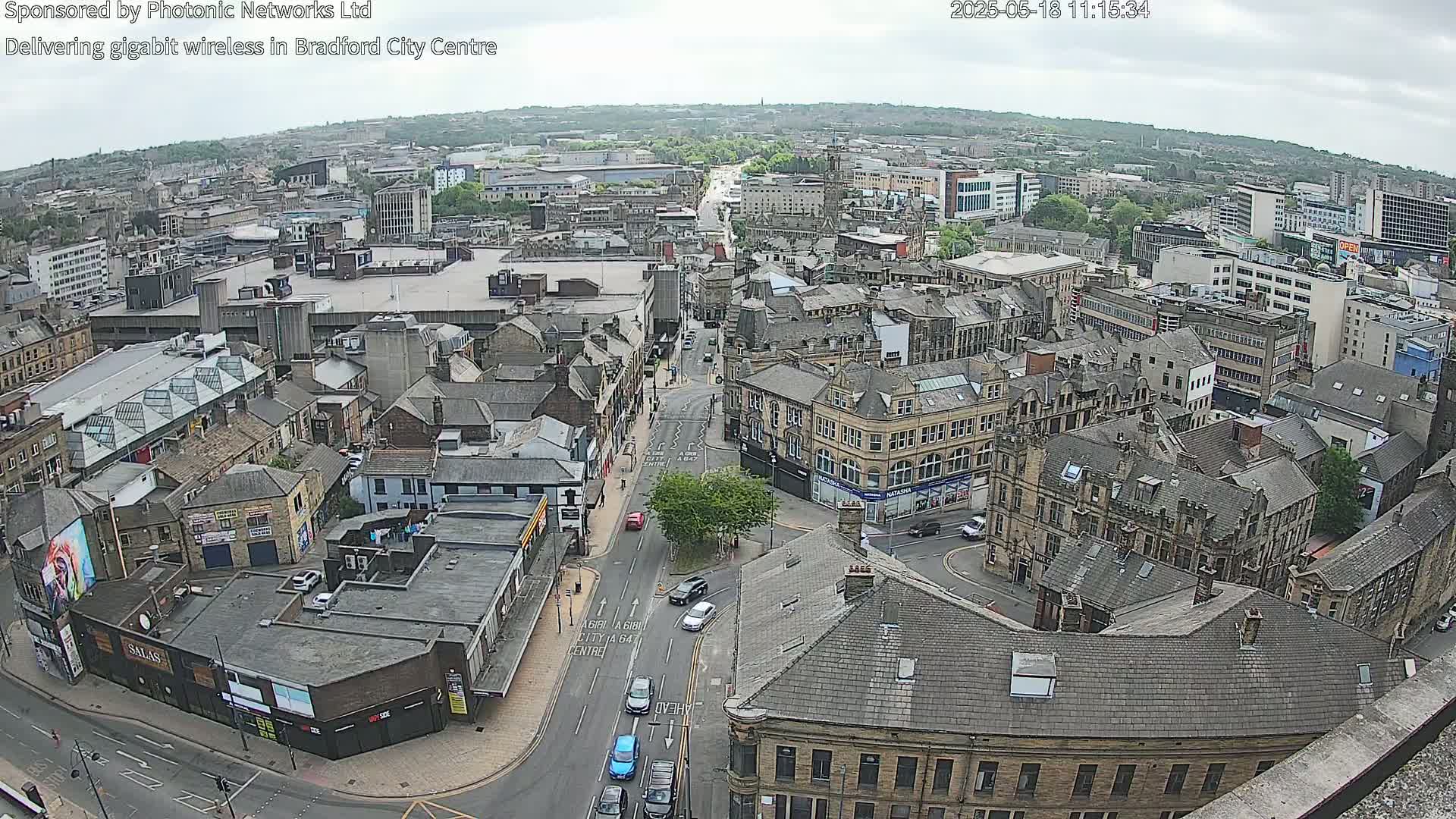 A high-angle view of a city center on an overcast day, showing numerous buildings and streets with sparse traffic.