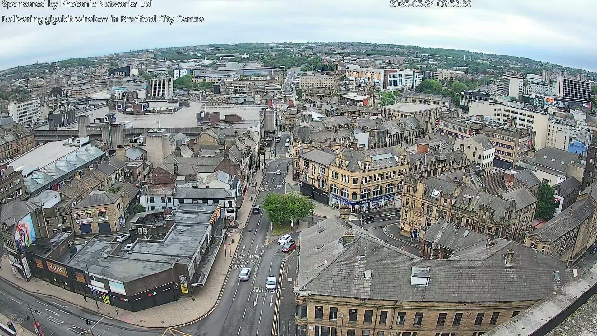An elevated view of a city center on an overcast day, showing numerous buildings and streets with some cars visible.