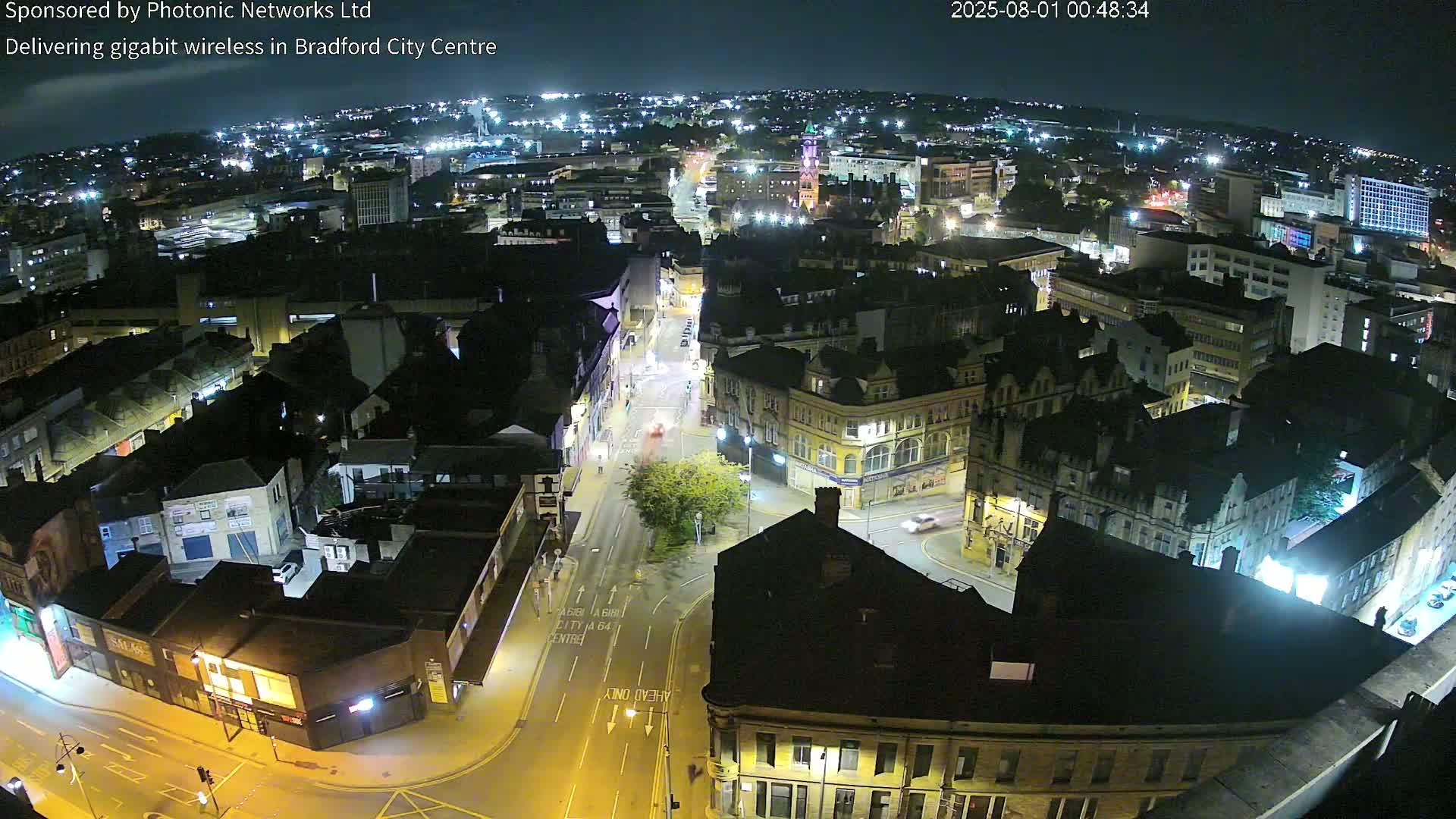 A nighttime, high-angle view of a city center with illuminated buildings and streets, showing minimal traffic.