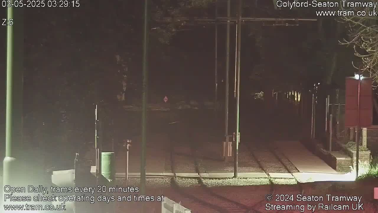 A nighttime view of tram tracks and a station platform, illuminated by artificial lights.