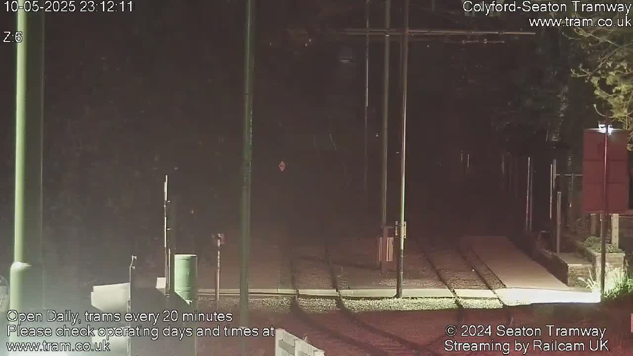 A nighttime view of a tram track, with dark surroundings and streetlights illuminating the area.