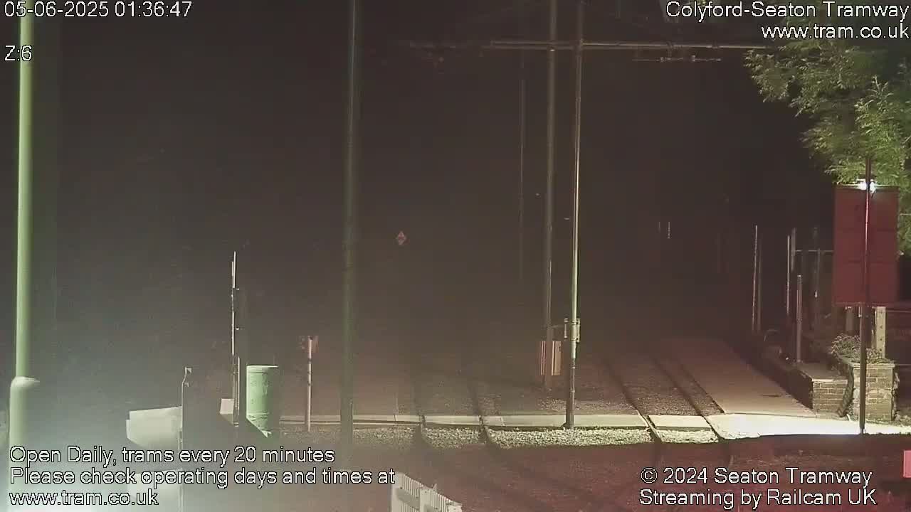 A nighttime view of empty tram tracks at a station, under a dark sky.