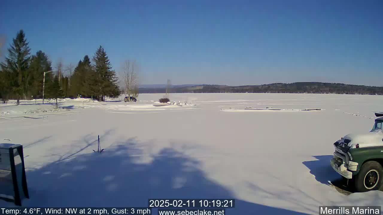A snow-covered marina with a frozen lake in the background under a clear blue sky.